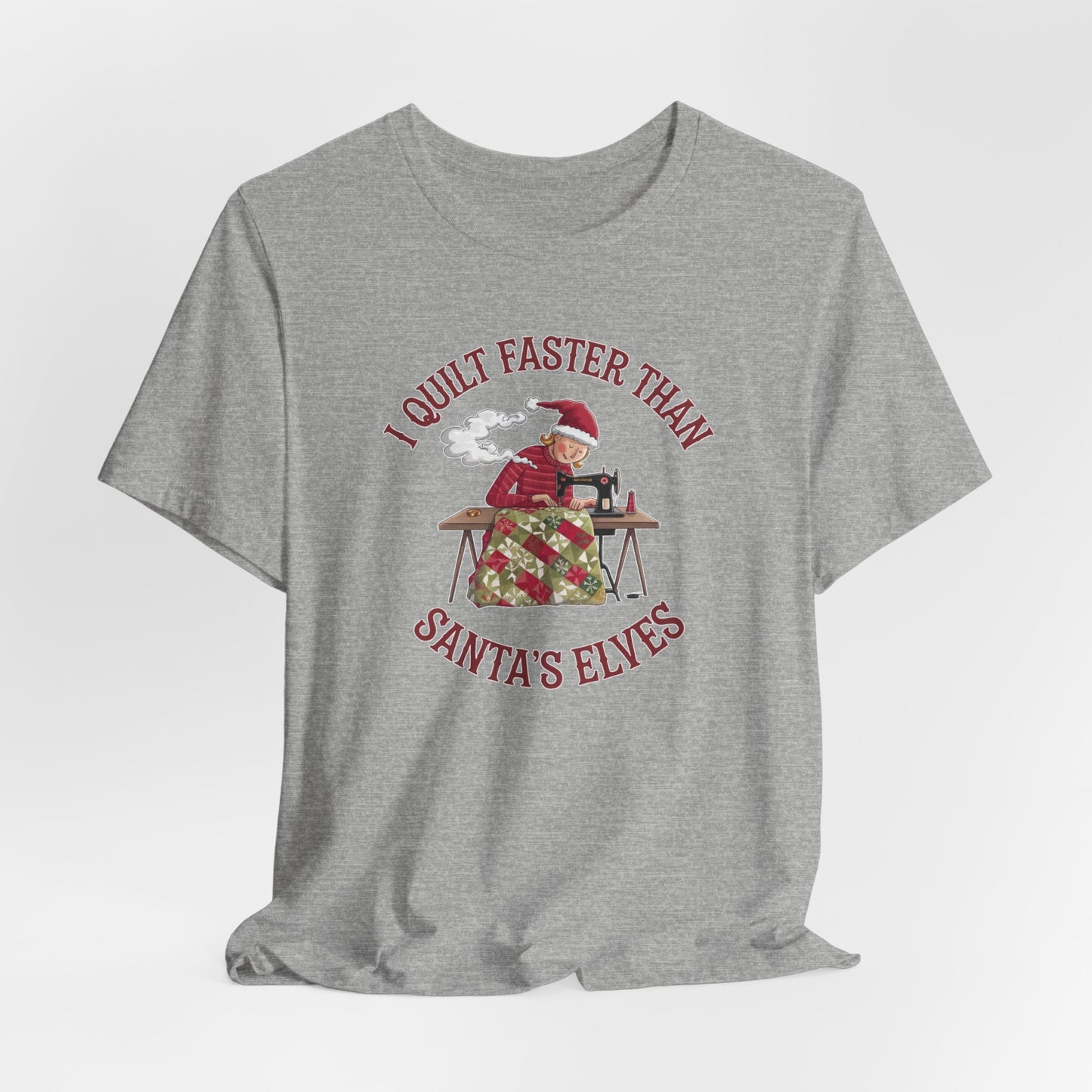 An Athletic Heather christmas quilting t-shirt featuring a quilter working at a sewing machine, quilting a festive holiday quilt, with the phrase "I Quilt Faster Than Santa's Elves" above the image, highlighting the speed and skill of the quilter.