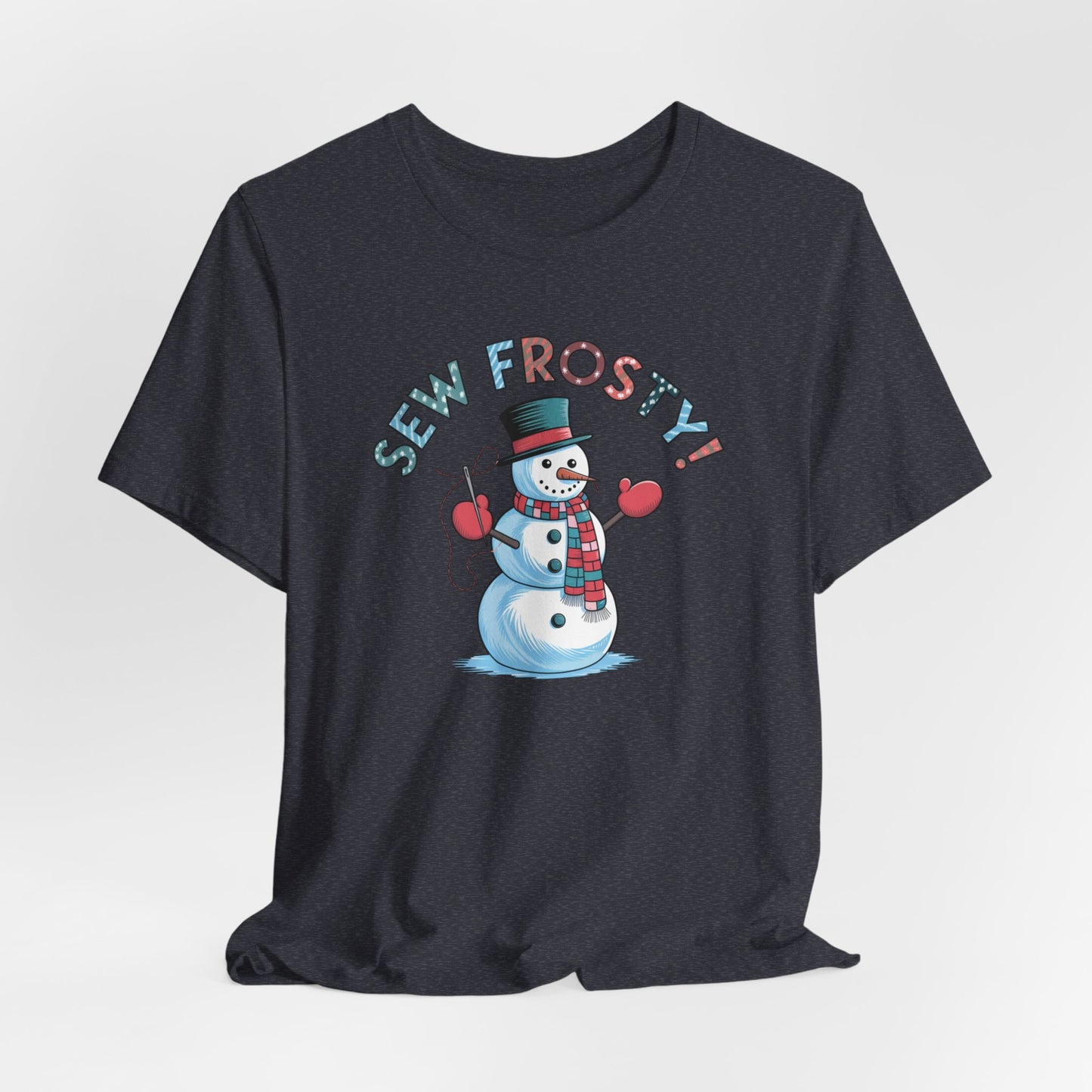 A Heather Navy christmas quilting t-shirt featuring cheerful snowman design holding a sewing needle, with the phrase "Sew Frosty" in playful, winter-themed lettering. The snowman is wearing a scarf and mittens, ready for holiday sewing fun.