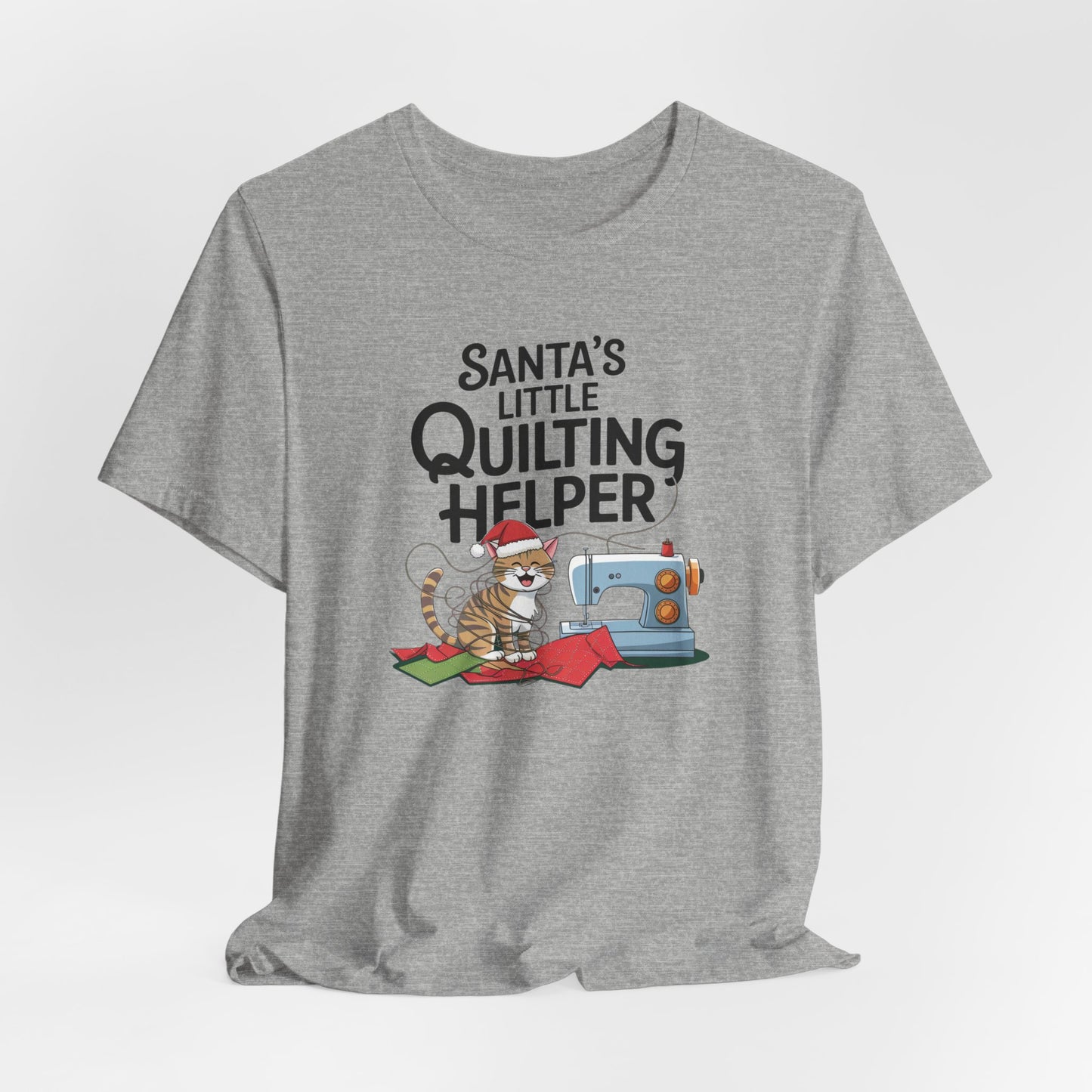 An Athletic Heather christmas quilting t-shirt featuring a playful cat wearing a Santa hat is tangled in thread next to a sewing machine, with the phrase "Santa's Little Quilting Helper" above, combining quilting and holiday humor.