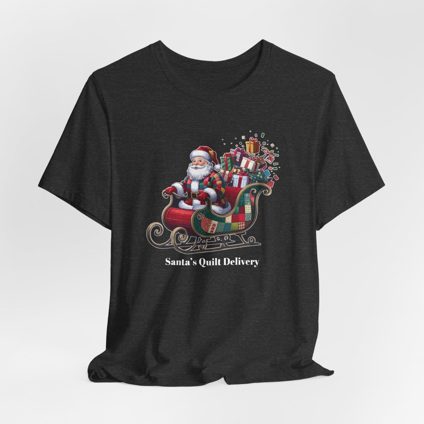 A Dark Grey Heather christmas quilting t-shirt featuring Santa Claus wearing a patchwork quilt coat, sitting in a sleigh filled with gifts and quilts, with the phrase "Santa's Quilt Delivery" below, combining holiday cheer and quilting fun.