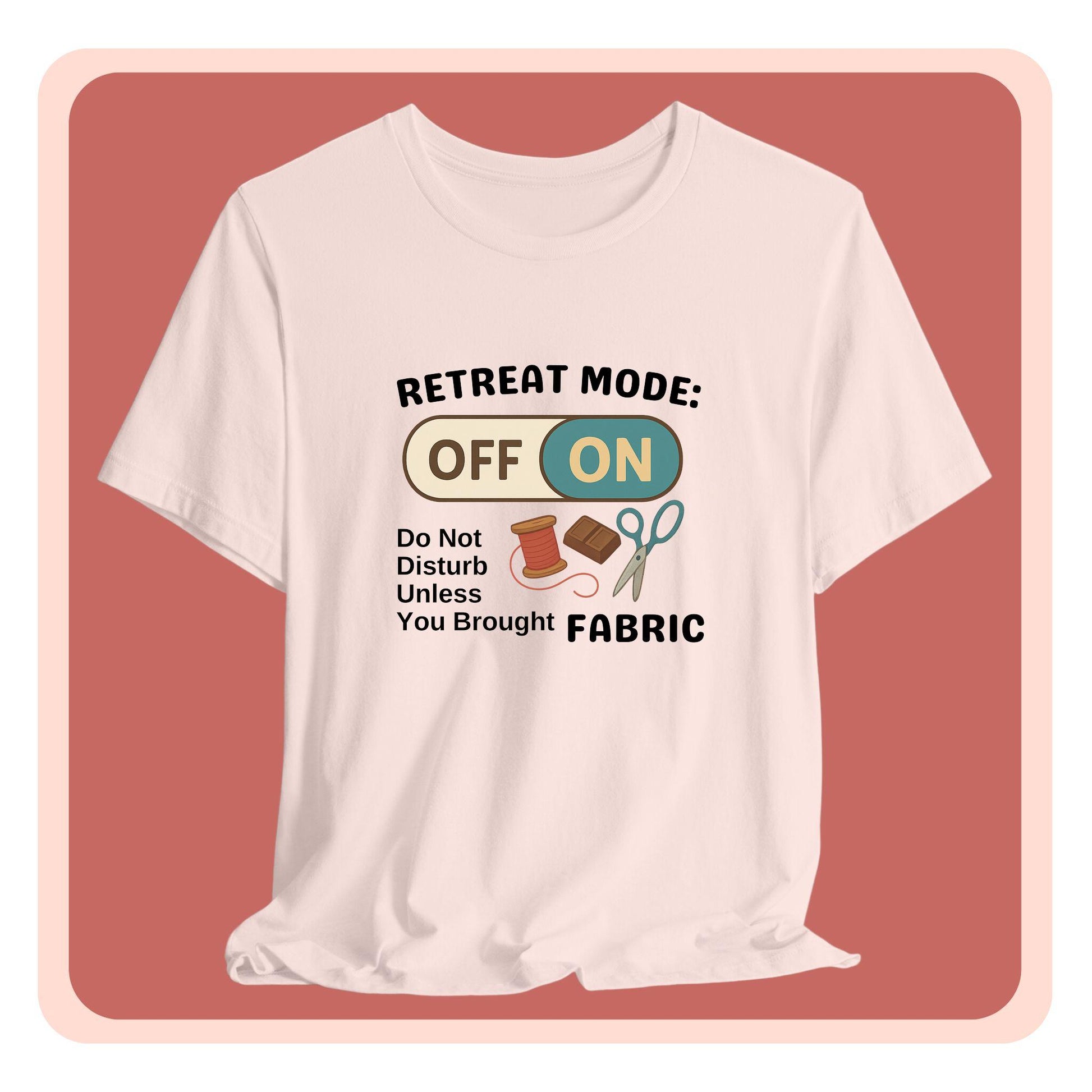 A A t-shirt with a toggle switch that says "Retreat Mode: OFF/ON" surrounded by a spool of thread, chocolate, and scissors. Text below reads "Do not disturb unless you brought fabric." Fun gift for quilting retreats.
