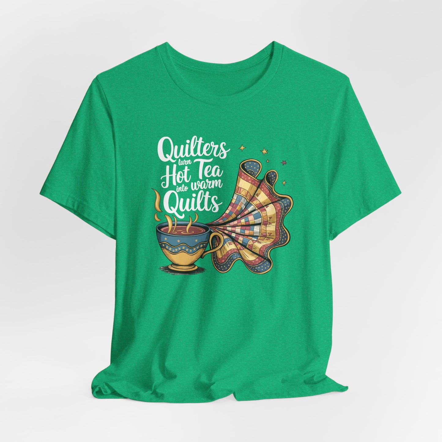 A Heather Kelly t-shirt with a whimsical design of a teacup transforming into a patchwork quilt, accompanied by the phrase 'Quilters turn hot tea into warm quilts.' Ideal for quilters and tea lovers