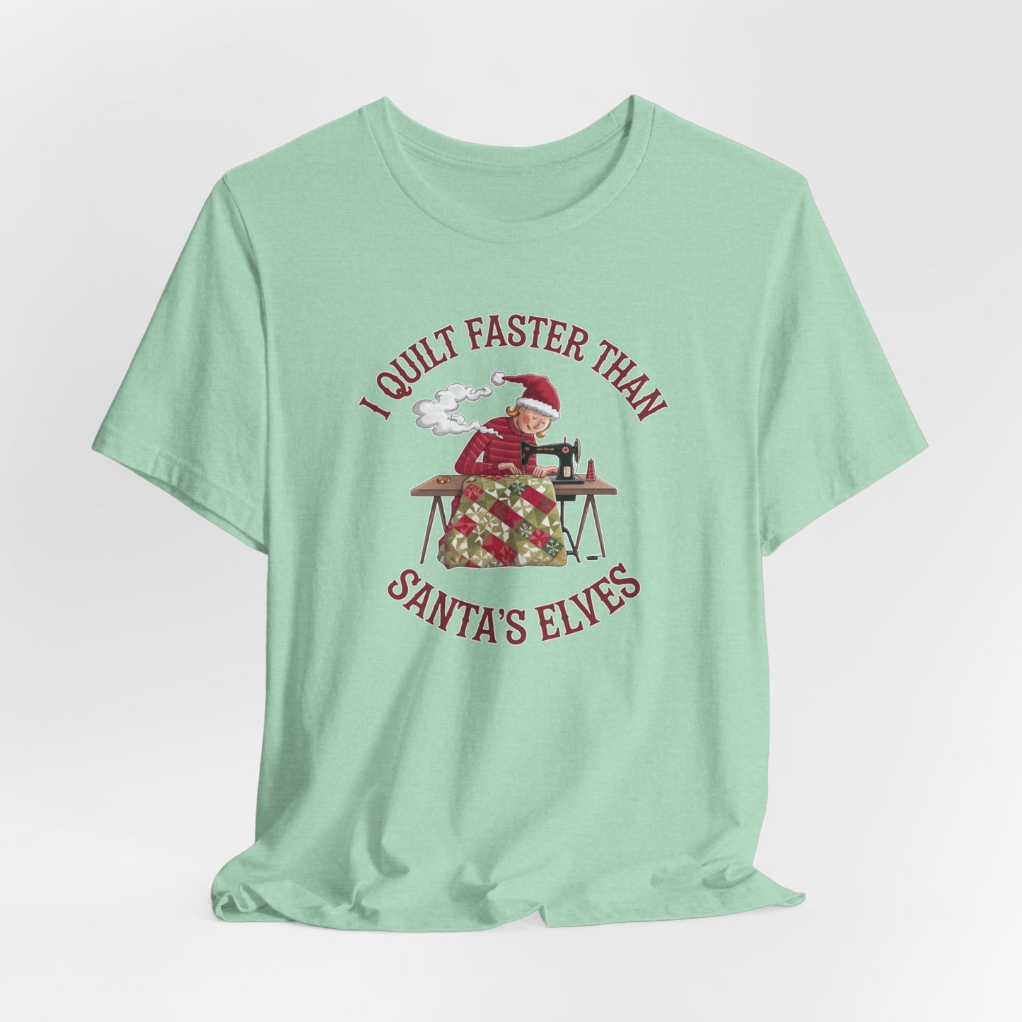 A Heather Mint christmas quilting t-shirt featuring a quilter working at a sewing machine, quilting a festive holiday quilt, with the phrase "I Quilt Faster Than Santa's Elves" above the image, highlighting the speed and skill of the quilter.