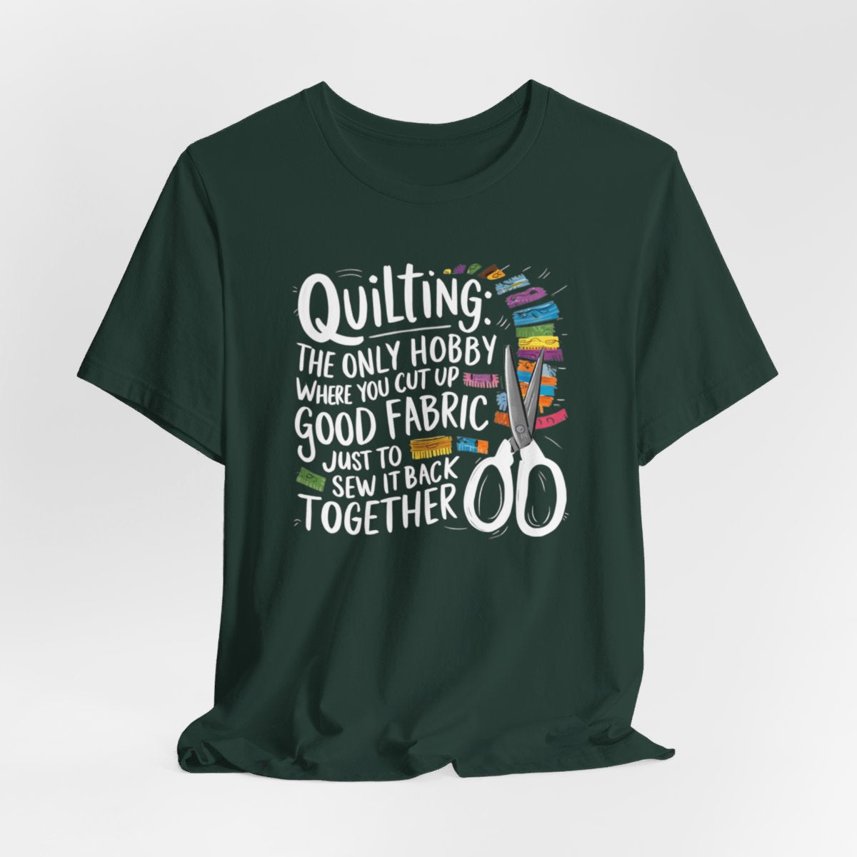 A Forest Quilting-themed T-Shirt with text "Quilting: The Only Hobby Where You Cut Up Good Fabric Just to Sew it Back Together" surrounded by colorful fabric scraps and scissors.