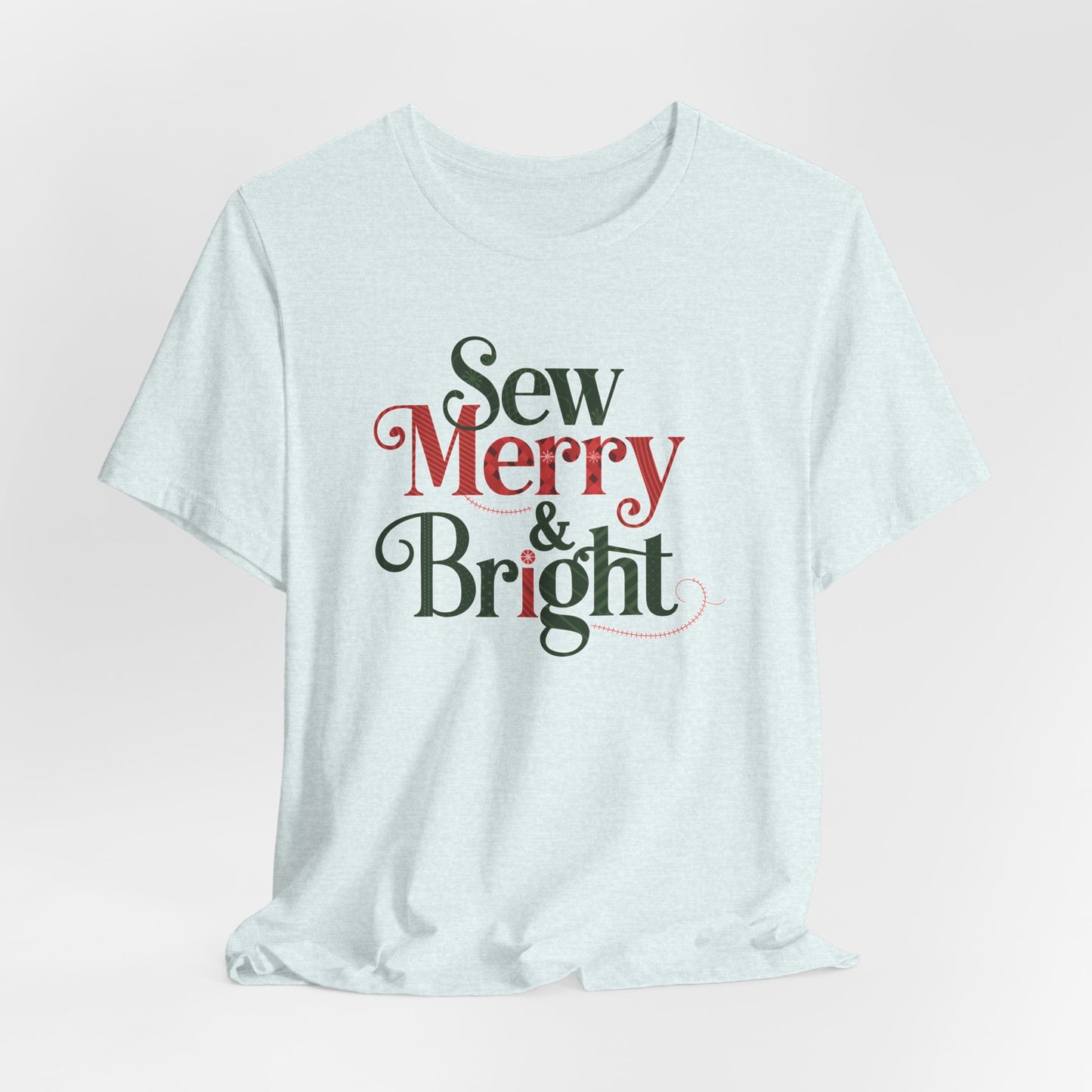 A Heather Ice Blue t-shirt with the phrase "Sew Merry & Bright," incorporating sewing-inspired elements and holiday-themed accents, such as stitching lines and festive patterns.