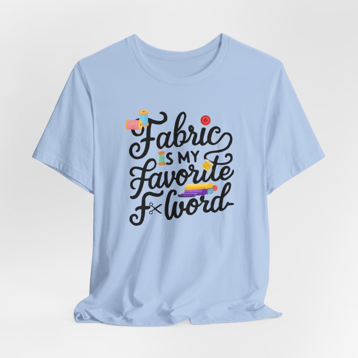 A Baby Blue T-Shirt with the phrase Fabric is My Favorite F-Word in a bold font with thread, buttons, and fabric bolts