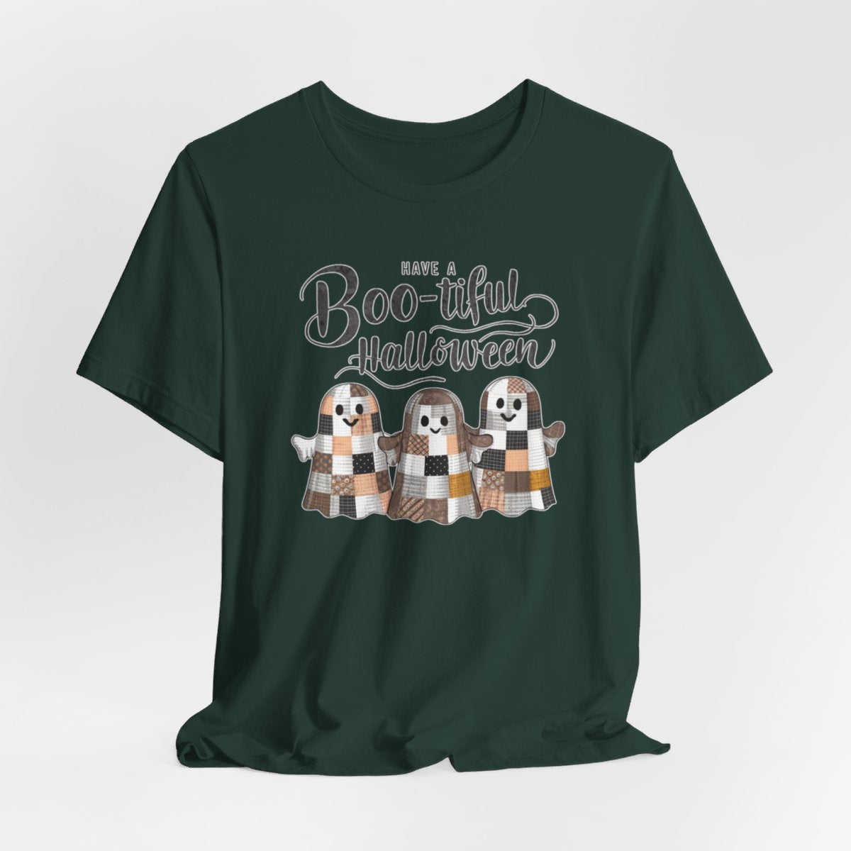 A Halloween Quilting T-Shirt featuring three smiling patchwork ghosts made of various quilt patterns in autumn colors. Text reads "Have a Boo-tiful Halloween" in stylized lettering. Perfect for quilters who love Halloween.
