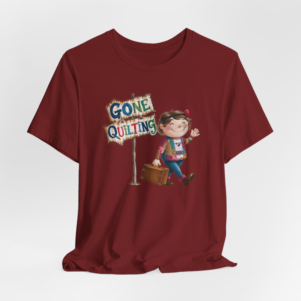 A Cardinalfun quilting T-Shirt with a cartoon illustration of a smiling girl wearing a patchwork jacket, carrying a suitcase next to a wooden sign that reads "Gone Quilting" in colorful letters.
