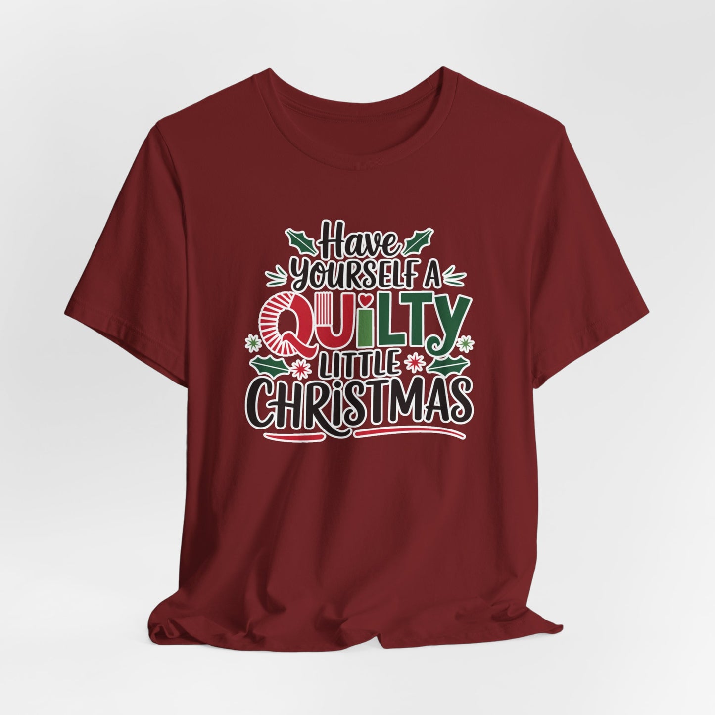A Cardinal fun holiday-themed t-shirt featuring the phrase "Have Yourself a Quilty Little Christmas" with quilting-inspired elements and holiday decorations such as holly and stars.
