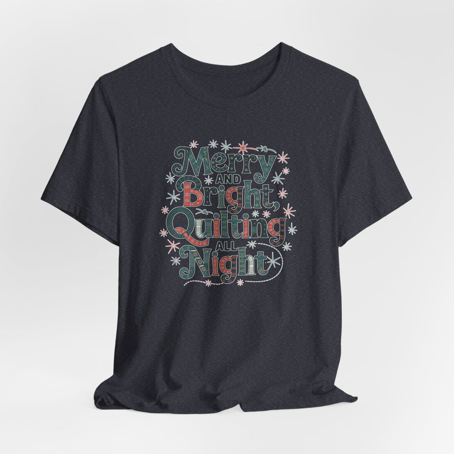 A Heather Navy christmas quilting T-shirt featuring a whimsical design with the phrase "Merry and Bright, Quilting All Night," featuring festive quilting patterns and holiday-themed elements like stars and stitching lines. Perfect gift for quilters.