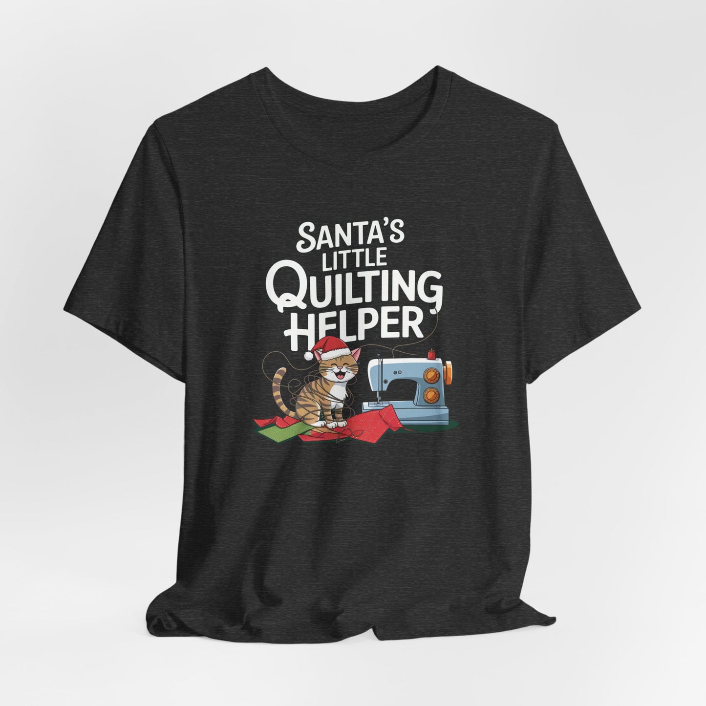 A Dark Grey Heather christmas quilting t-shirt featuring a playful cat wearing a Santa hat is tangled in thread next to a sewing machine, with the phrase "Santa's Little Quilting Helper" above, combining quilting and holiday humor.