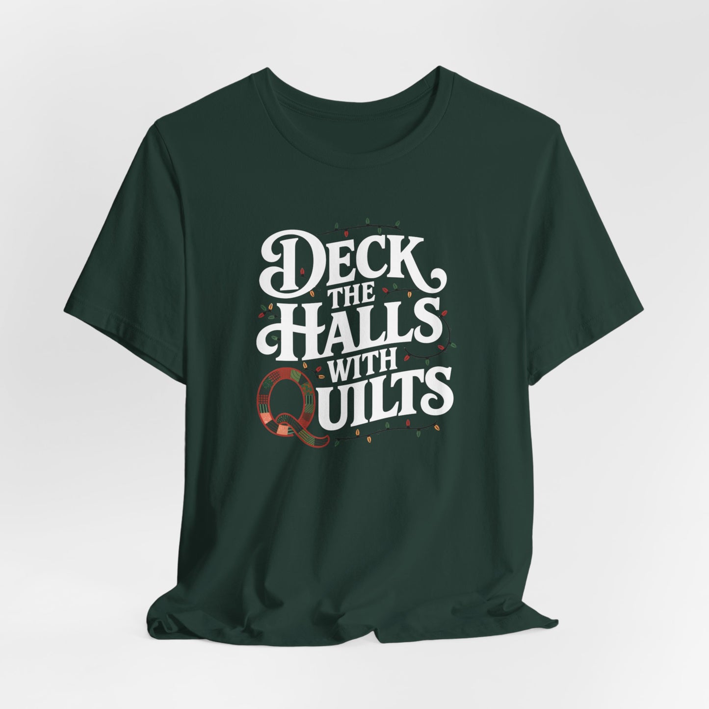 A Forest christmas quilting t-shirt featuring the phrase "Deck the Halls with Quilts," adorned with holiday lights and quilting-inspired elements, including a quilted 'Q' for a humorous touch.