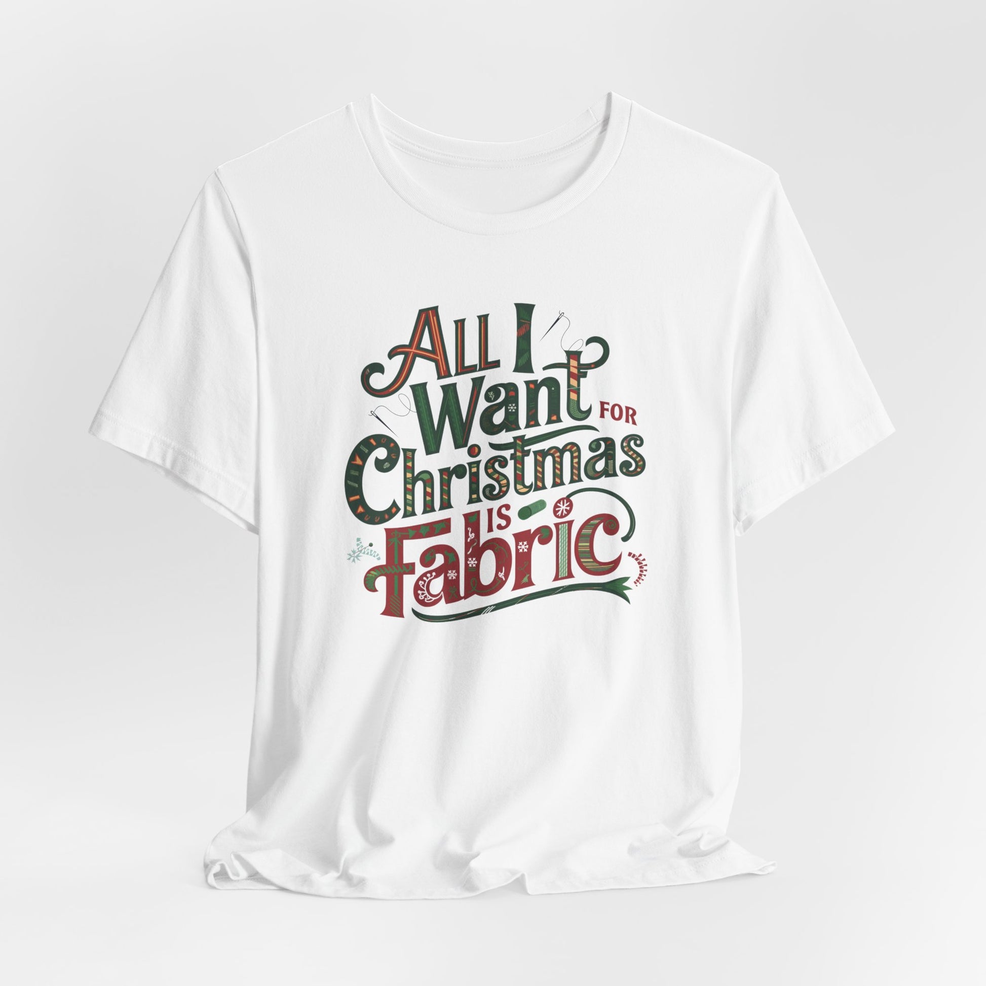 A White festive quilting christmas T-shirt featuring the phrase "All I Want for Christmas is Fabric," with fun sewing and quilting accents like needles and threads swirling around the text.