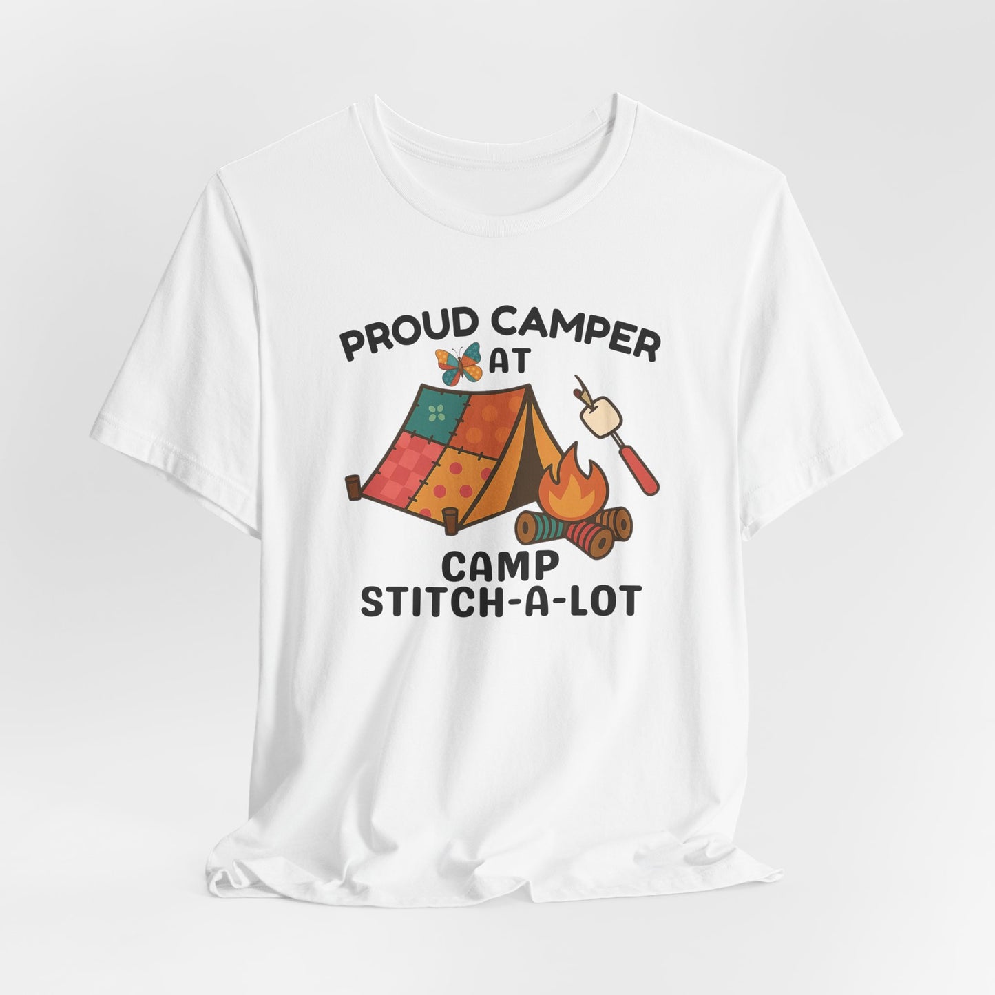 A A White t-shirt featuring a colorful design with a patchwork tent, thread spool campfire, marshmallow on a seam ripper stick, and a butterfly. Text reads "Proud Camper at Camp Stitch-a-Lot." Fun gift for quilting retreats.