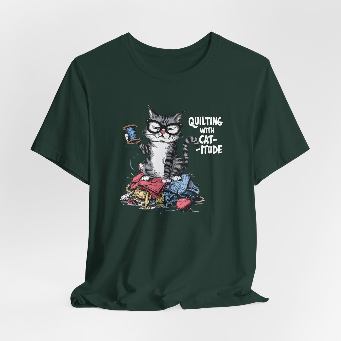 A Forest t-shirt featuring a sassy cartoon cat sitting on a pile of colorful fabric, holding a spool of thread, with the phrase 'Quilting with Cat-itude,' perfect for quilters and cat lovers.