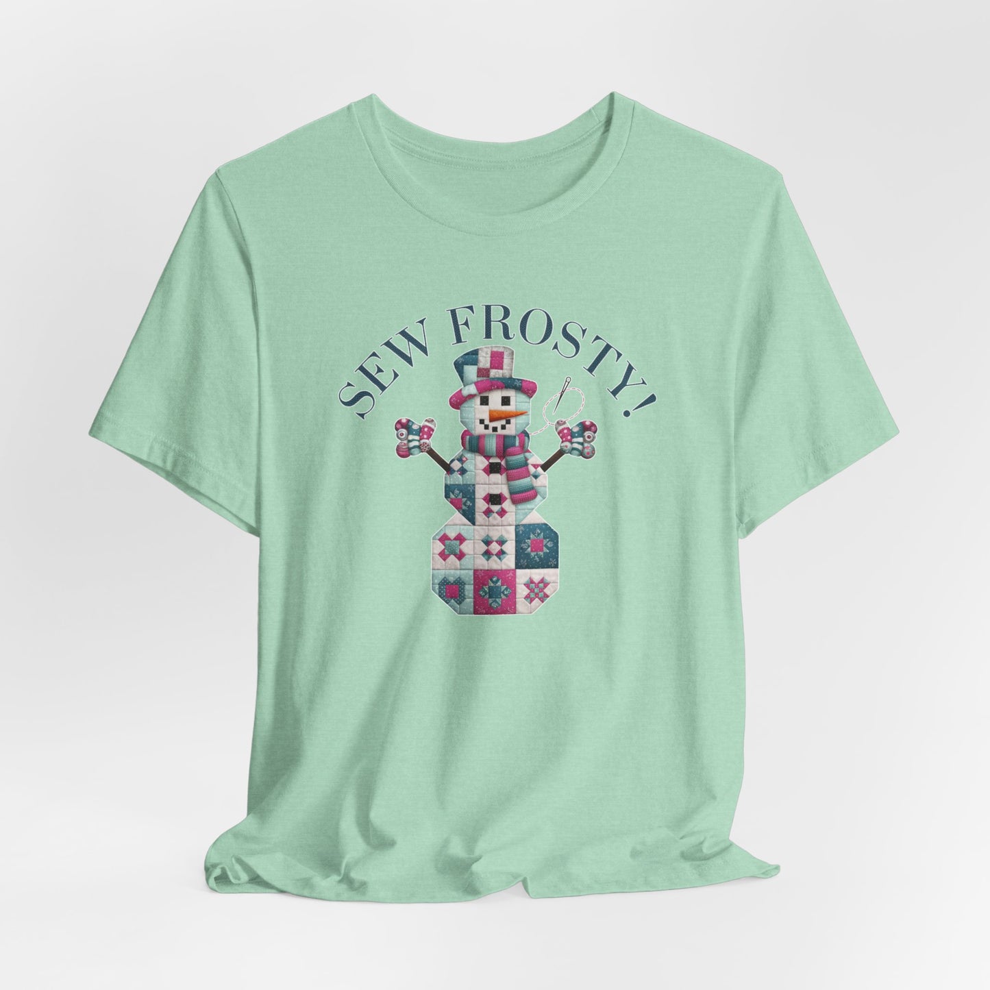 A Heather Mint christmas quilting t-shirt featuring cute snowman made of patchwork quilt blocks with the phrase "Sew Frosty" above, holding a needle to highlight the quilting theme.