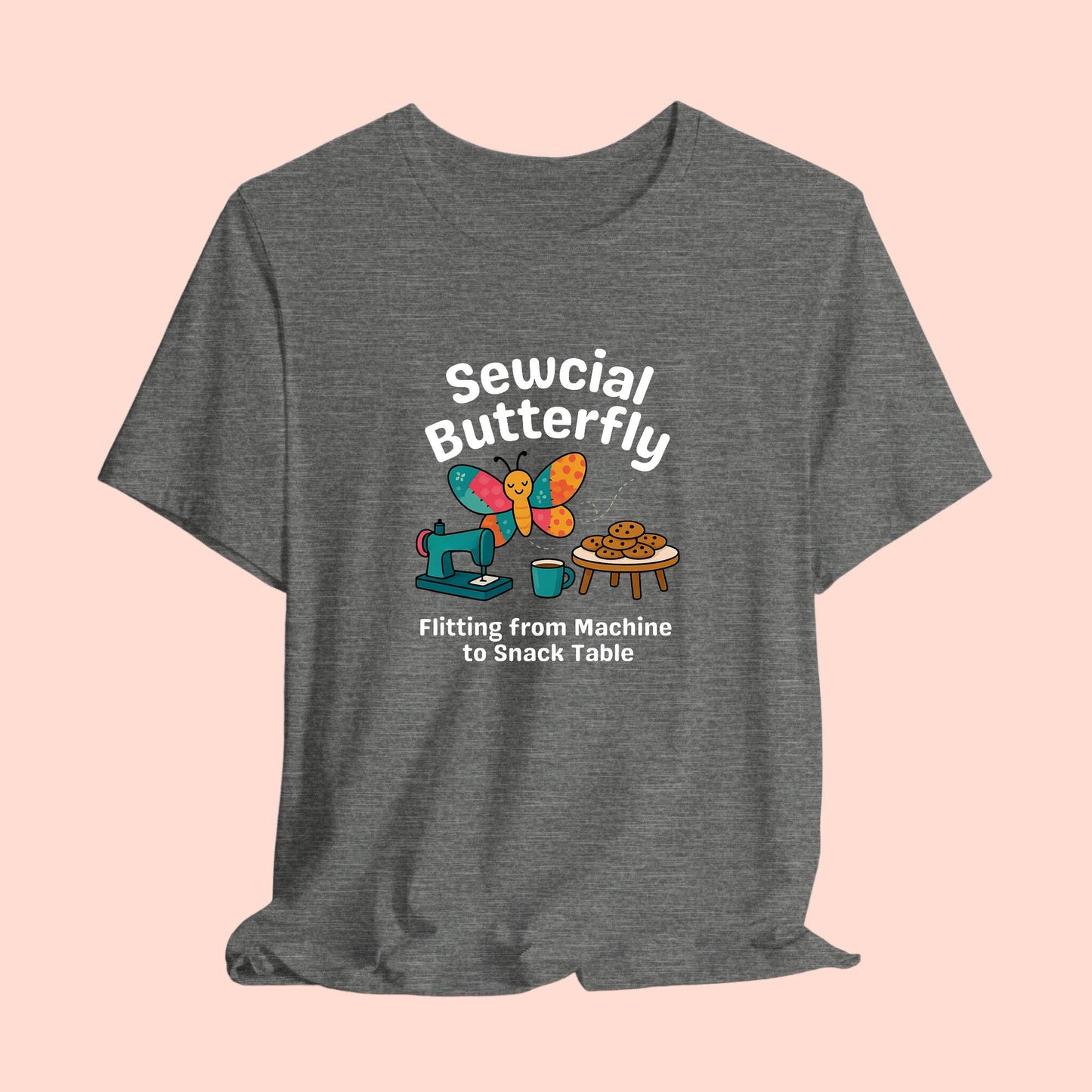 A A t-shirt with a colorful design showing a patchwork butterfly flying between a sewing machine and a table of cookies. Text reads “Sewcial Butterfly – Flitting from Machine to Snack Table.” Funny gift for quilters
