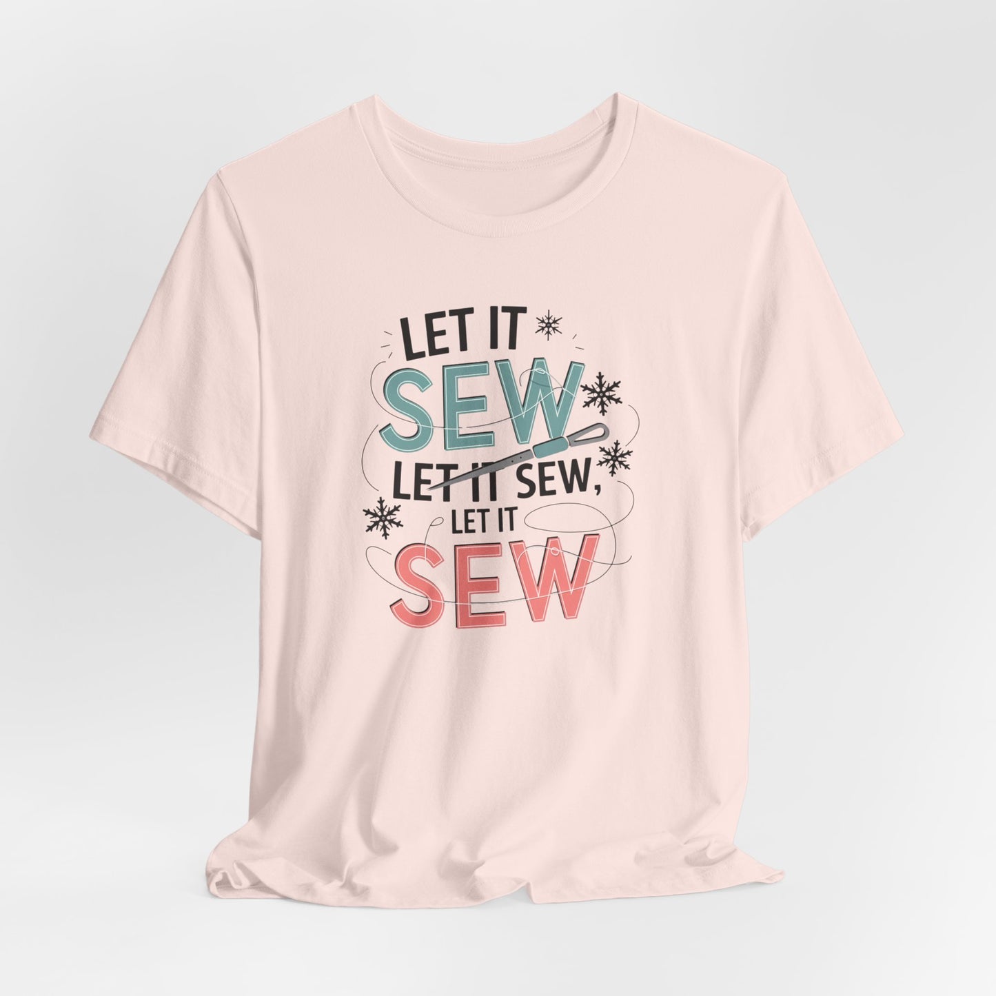 A Soft Pink christmas quilting t-shirt featuring the phrase "Let it Sew, Let it Sew, Let it Sew" featuring a needle and thread weaving through the letters, accented by snowflakes to bring out the holiday theme.