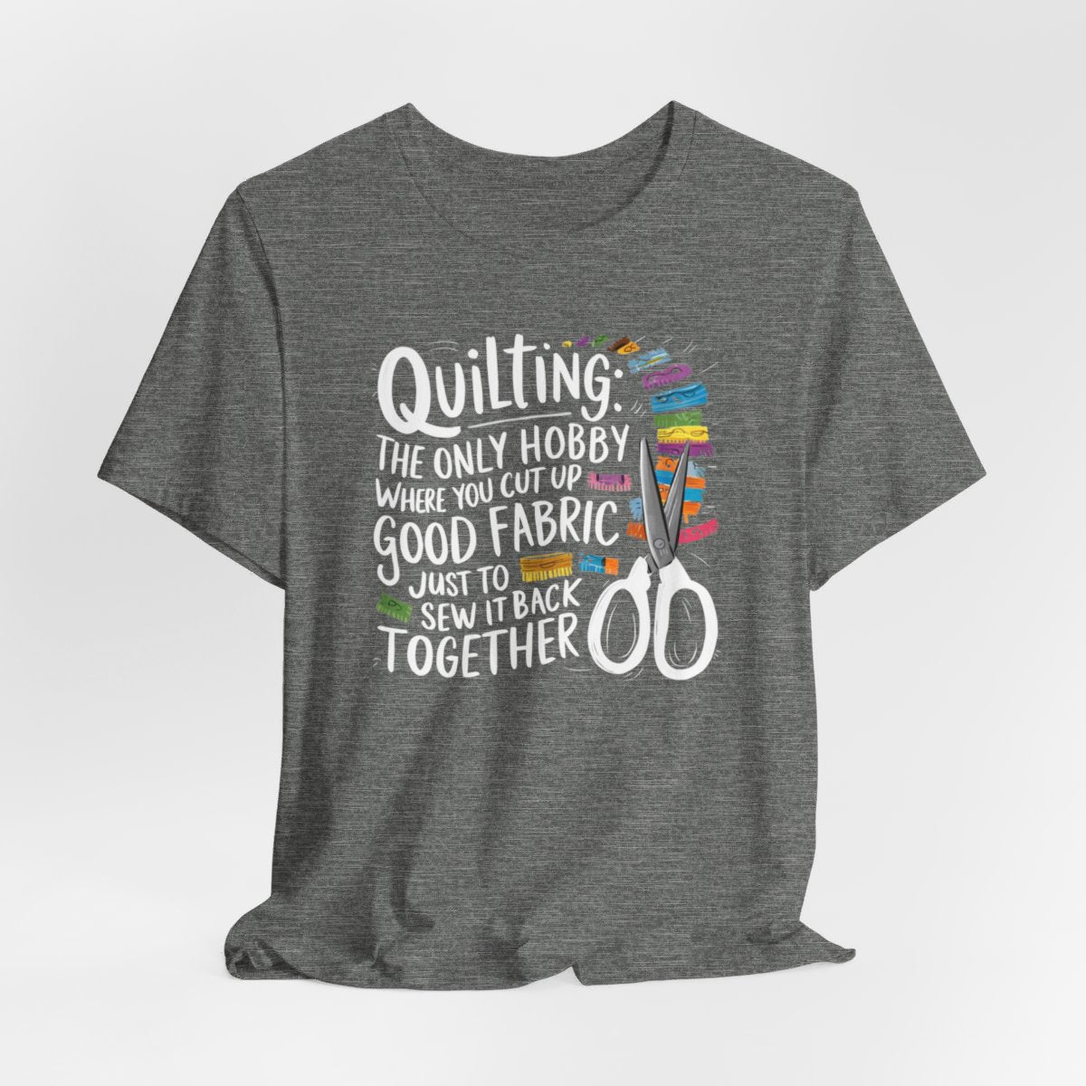 A Deep Heather Quilting-themed T-Shirt with text "Quilting: The Only Hobby Where You Cut Up Good Fabric Just to Sew it Back Together" surrounded by colorful fabric scraps and scissors.