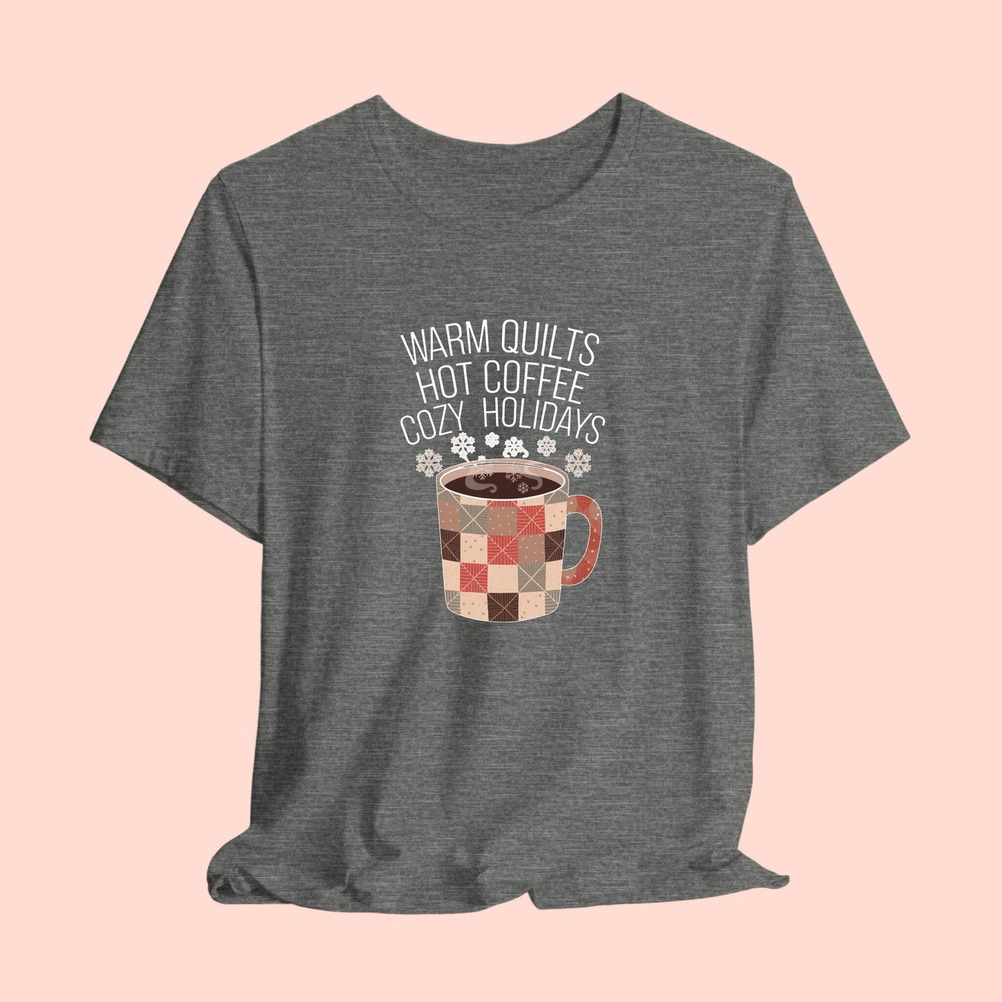 A christmas quilting t-shirt featuring a cozy patchwork quilt-themed coffee mug, surrounded by snowflakes, with the phrase "Warm Quilts, Hot Coffee, Cozy Holidays" above the mug, celebrating the warmth of quilts and coffee during the holiday season.