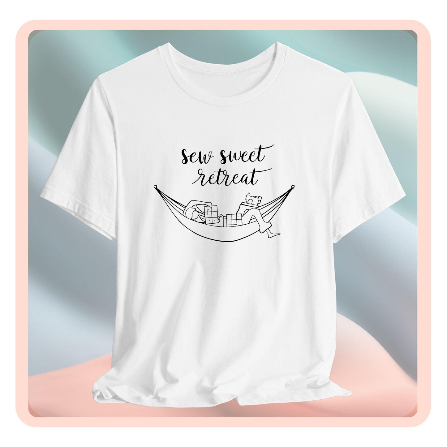 A T-Shirt with a black and white illustration of a hammock filled with quilting supplies like fabric squares and a sewing machine. Text above reads "Sew Sweet Retreat" in a flowing script font.
