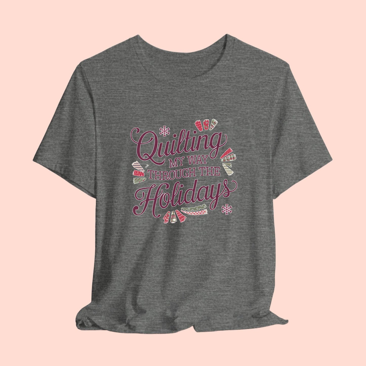 A playful holiday-themed t-shirt with the phrase "Quilting My Way Through the Holidays" surrounded by quilting-inspired decorations like fabric swatches and snowflakes.