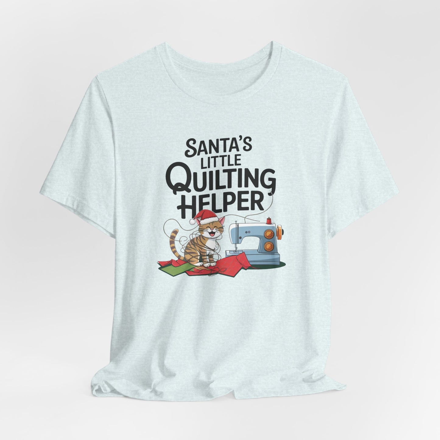A Heather Ice Blue christmas quilting t-shirt featuring a playful cat wearing a Santa hat is tangled in thread next to a sewing machine, with the phrase "Santa's Little Quilting Helper" above, combining quilting and holiday humor.