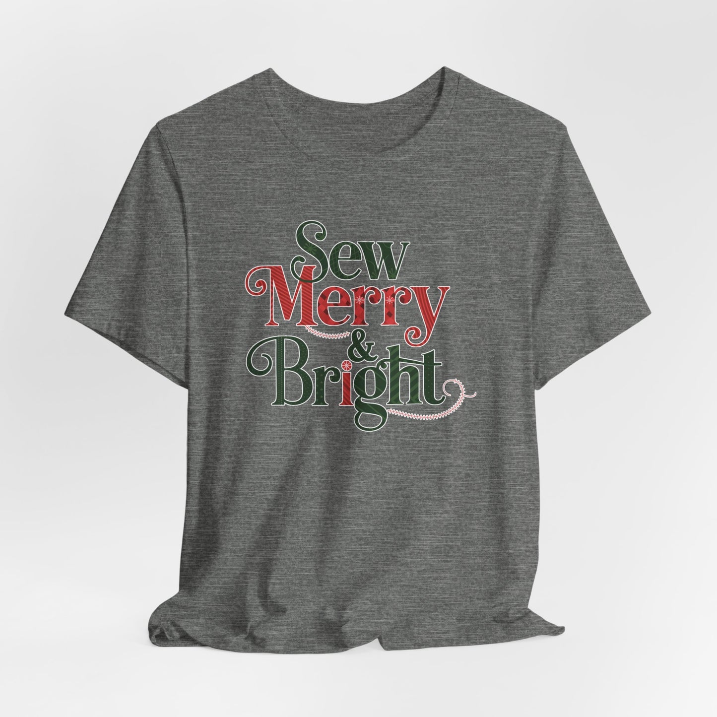 A Deep Heather t-shirt with the phrase "Sew Merry & Bright," incorporating sewing-inspired elements and holiday-themed accents, such as stitching lines and festive patterns.