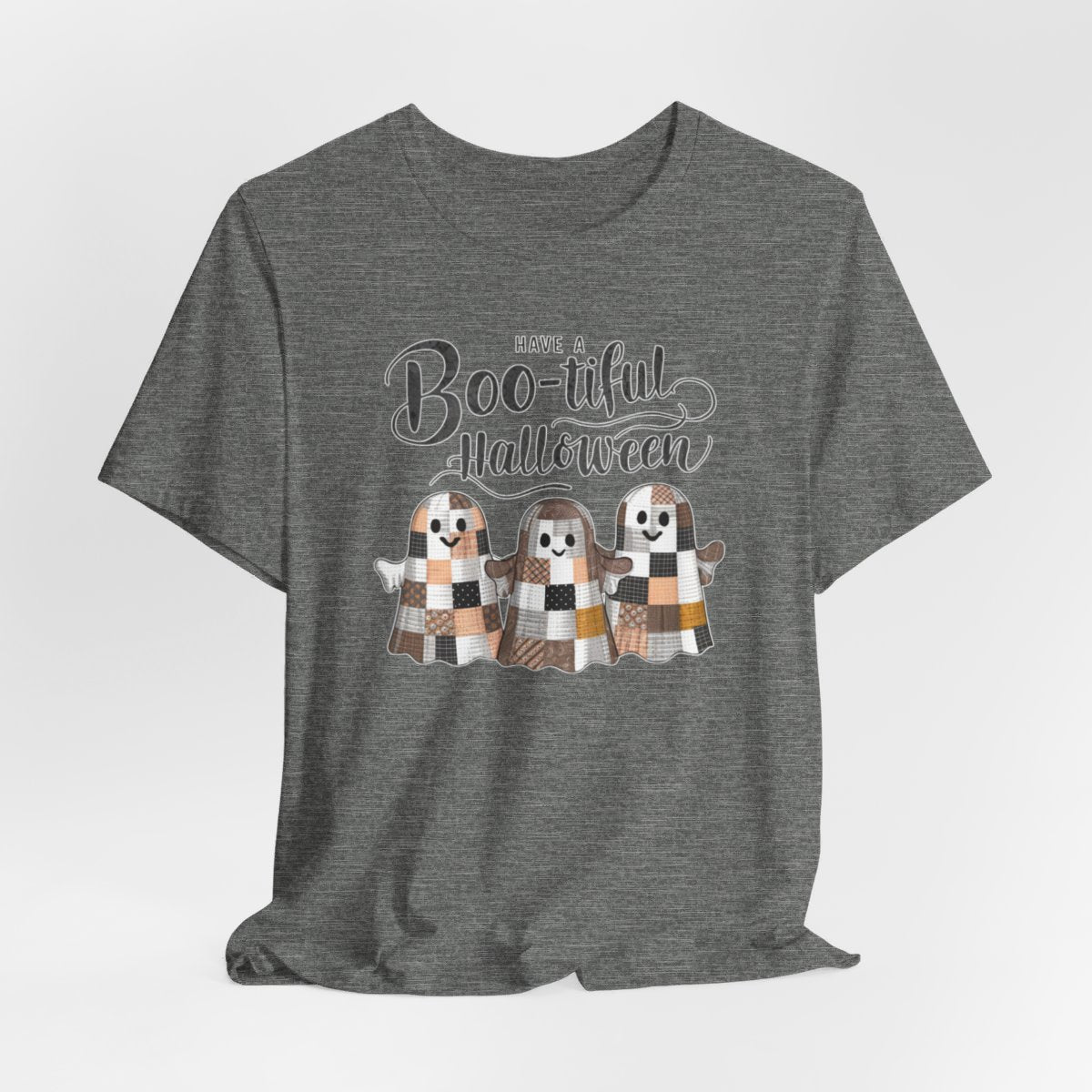 A Halloween Quilting T-Shirt featuring three smiling patchwork ghosts made of various quilt patterns in autumn colors. Text reads "Have a Boo-tiful Halloween" in stylized lettering. Perfect for quilters who love Halloween.