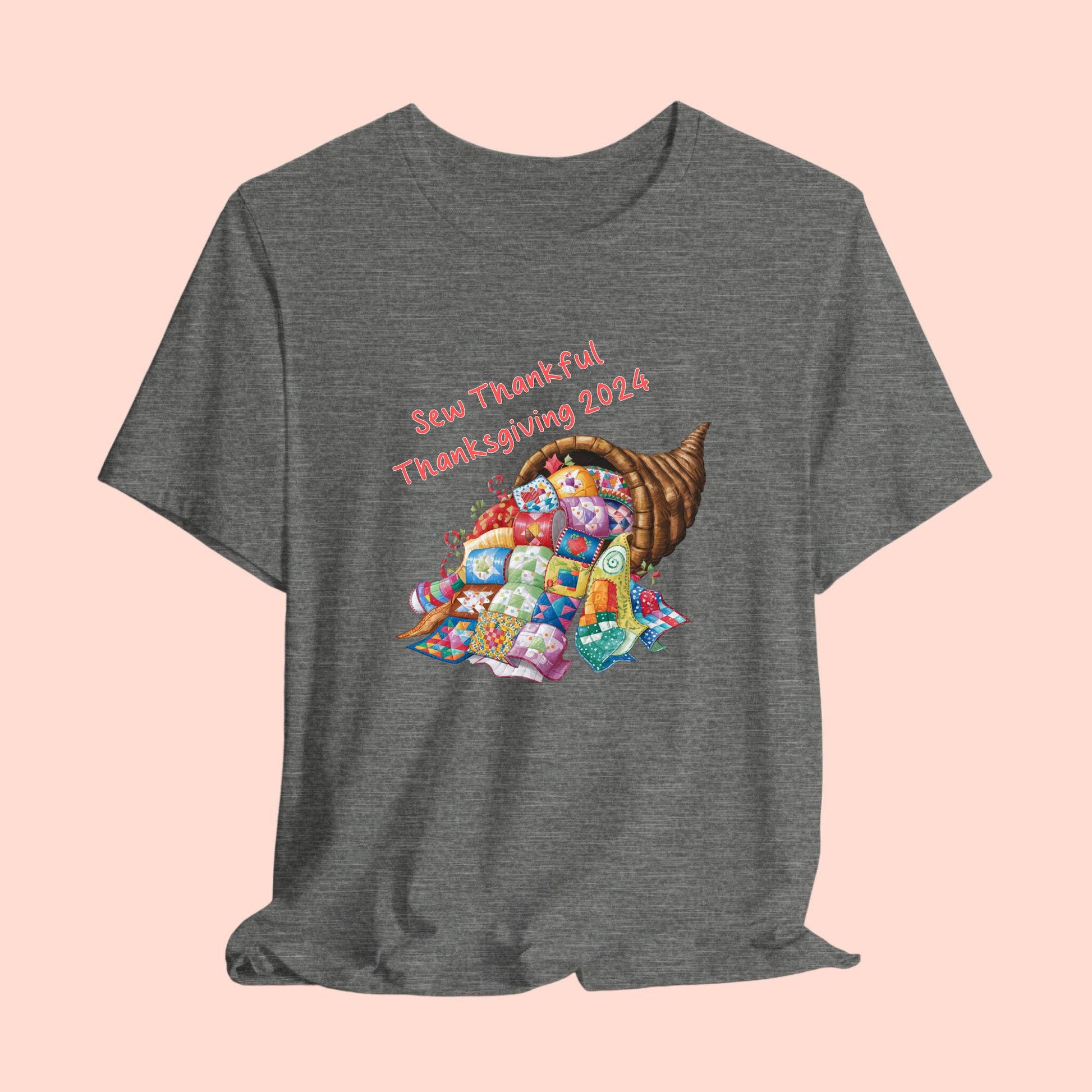 A thanksgiving  quilting t-shirt featuring a colorful quilted cornucopia overflowing with various quilt patterns and designs. Text reads "Sew Thankful Thanksgiving 2024" in red. Vibrant illustration combines quilting motifs with Thanksgiving imagery.