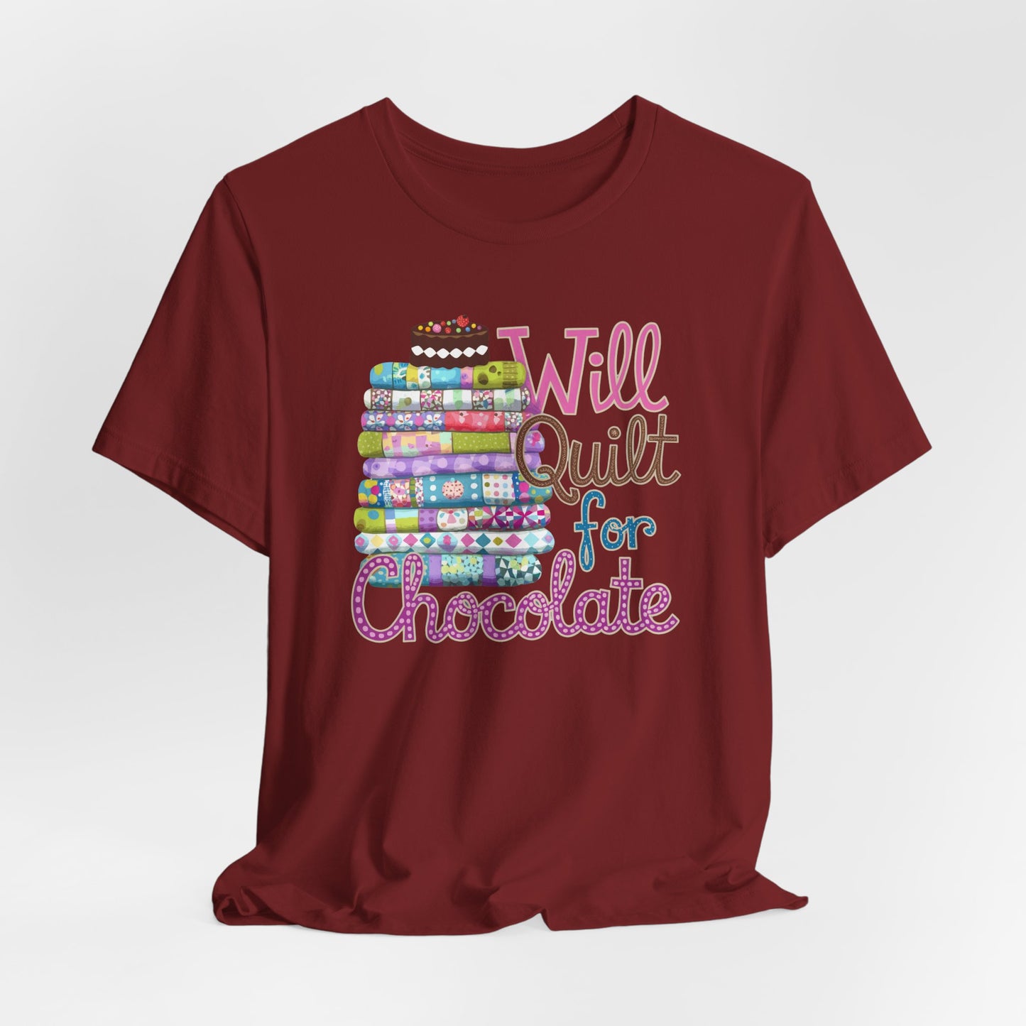 A Cardinal t-shirt featuring a whimsical design of a colorful stack of quilts topped with a chocolate cake and the phrase 'Will Quilt for Chocolate,' perfect for quilters who love sweets.