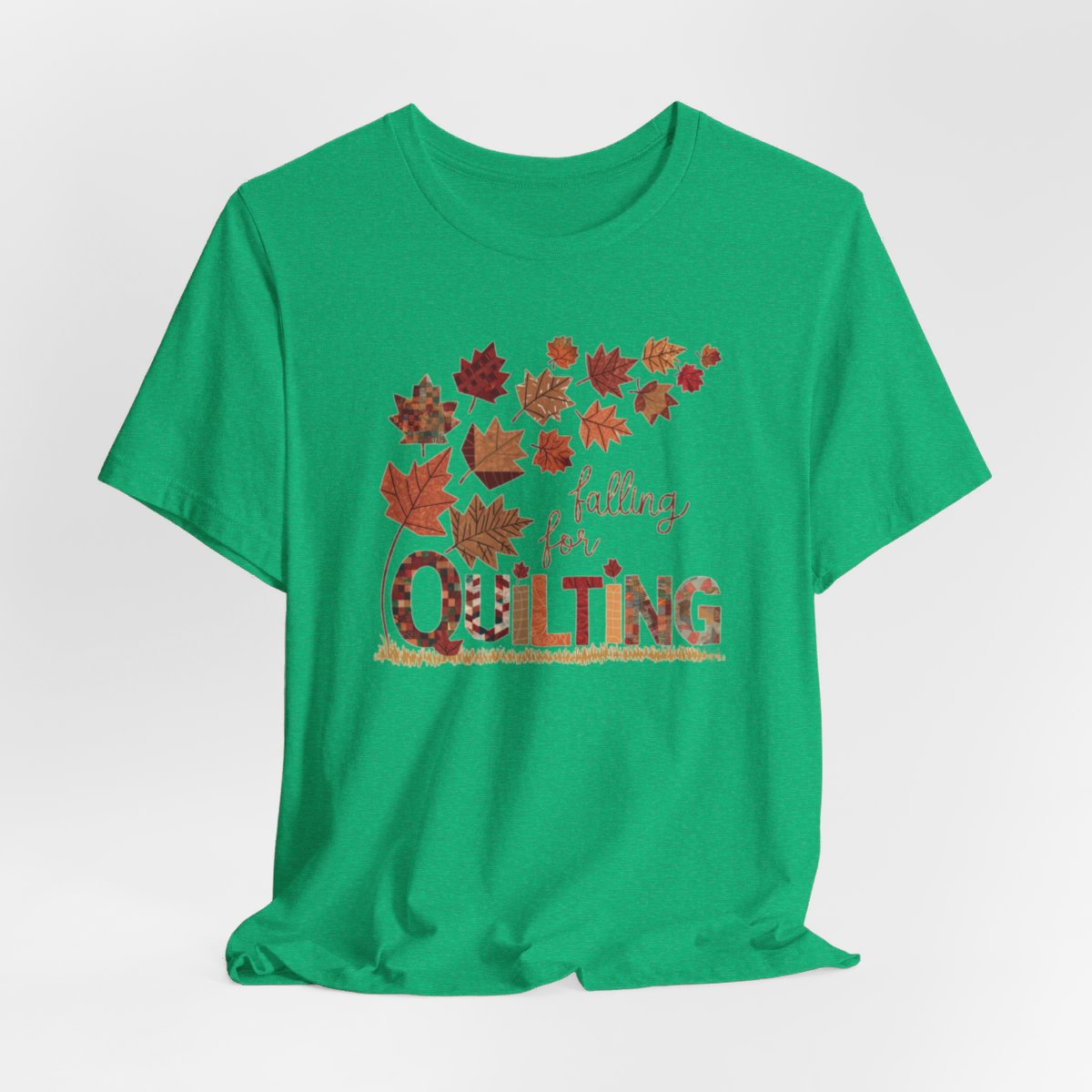 A Heather Kelly thanksgiving quilting t-shirt featuring autumn leaves with various quilting patterns inside. Text reads "falling for QUILTING" with letters in patchwork style. Warm fall colors and quilting motifs combine in a seasonal design.