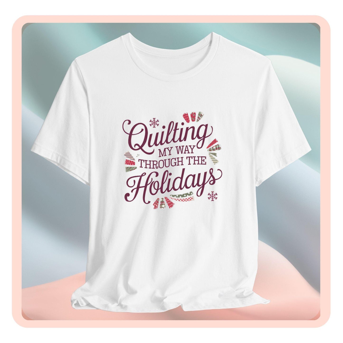 A playful holiday-themed t-shirt with the phrase "Quilting My Way Through the Holidays" surrounded by quilting-inspired decorations like fabric swatches and snowflakes.