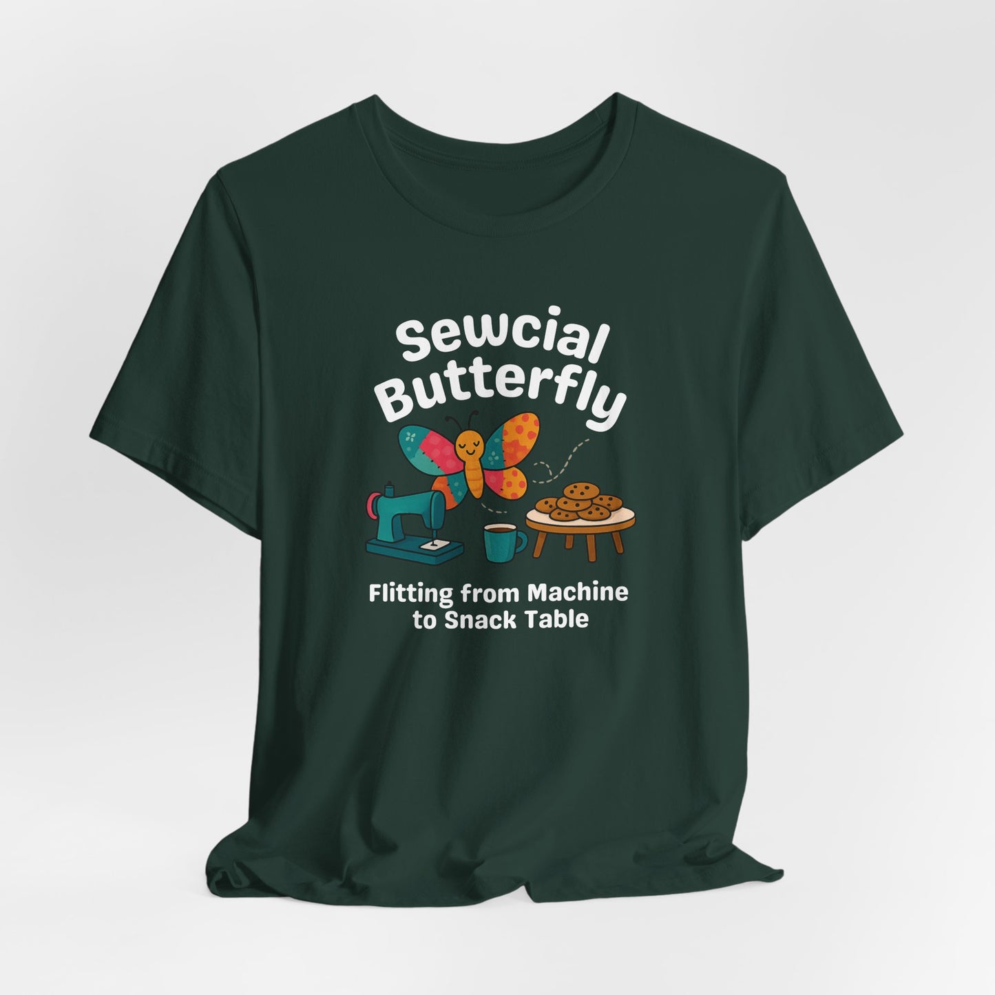 A A Forest t-shirt with a colorful design showing a patchwork butterfly flying between a sewing machine and a table of cookies. Text reads “Sewcial Butterfly – Flitting from Machine to Snack Table.” Funny gift for quilters