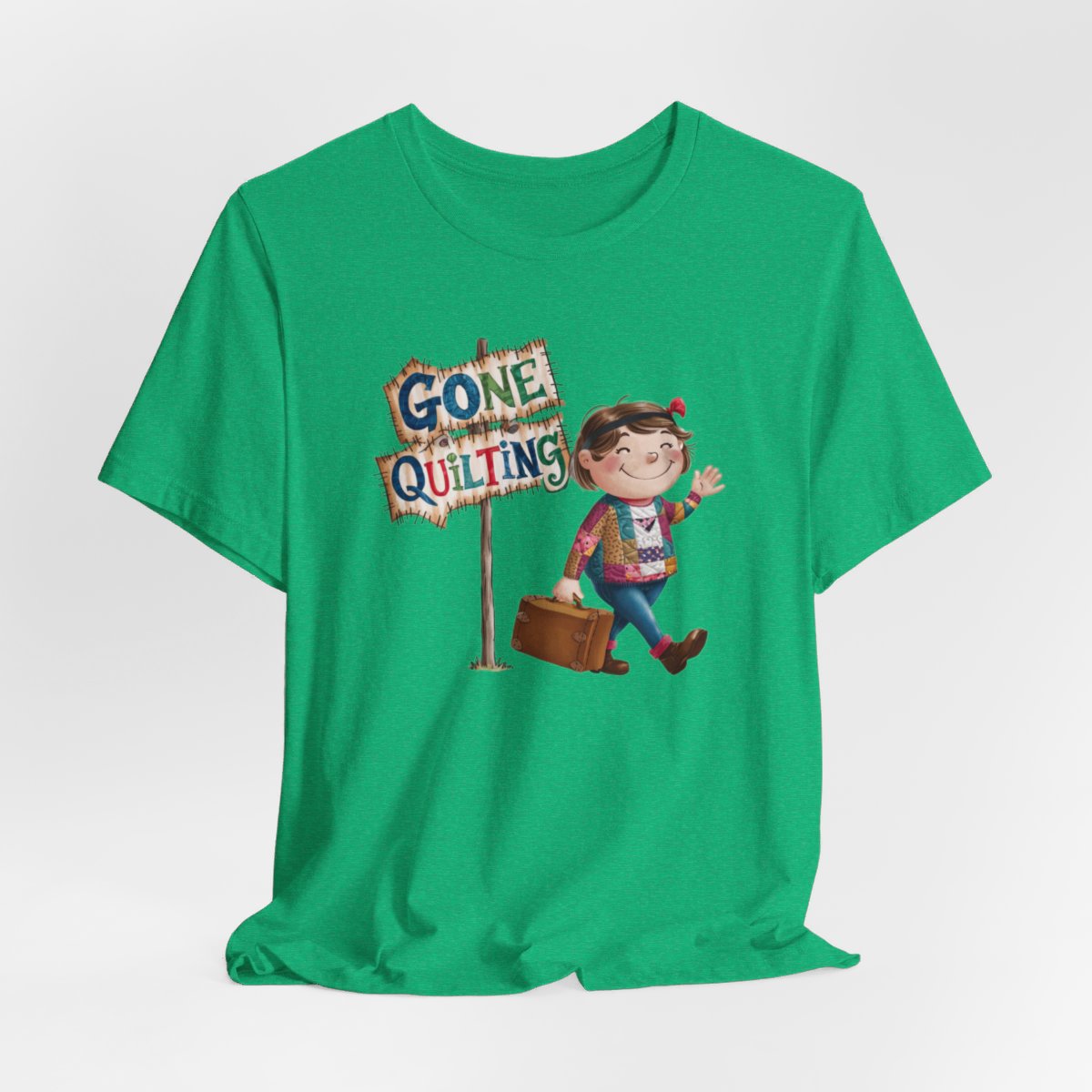 A Heather Kellyfun quilting T-Shirt with a cartoon illustration of a smiling girl wearing a patchwork jacket, carrying a suitcase next to a wooden sign that reads "Gone Quilting" in colorful letters.