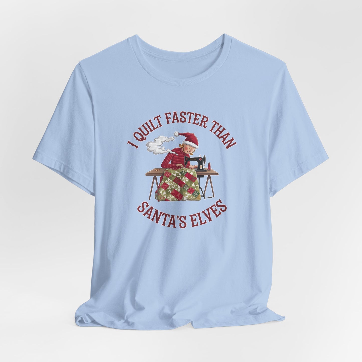 A Baby Blue christmas quilting t-shirt featuring a quilter working at a sewing machine, quilting a festive holiday quilt, with the phrase "I Quilt Faster Than Santa's Elves" above the image, highlighting the speed and skill of the quilter.