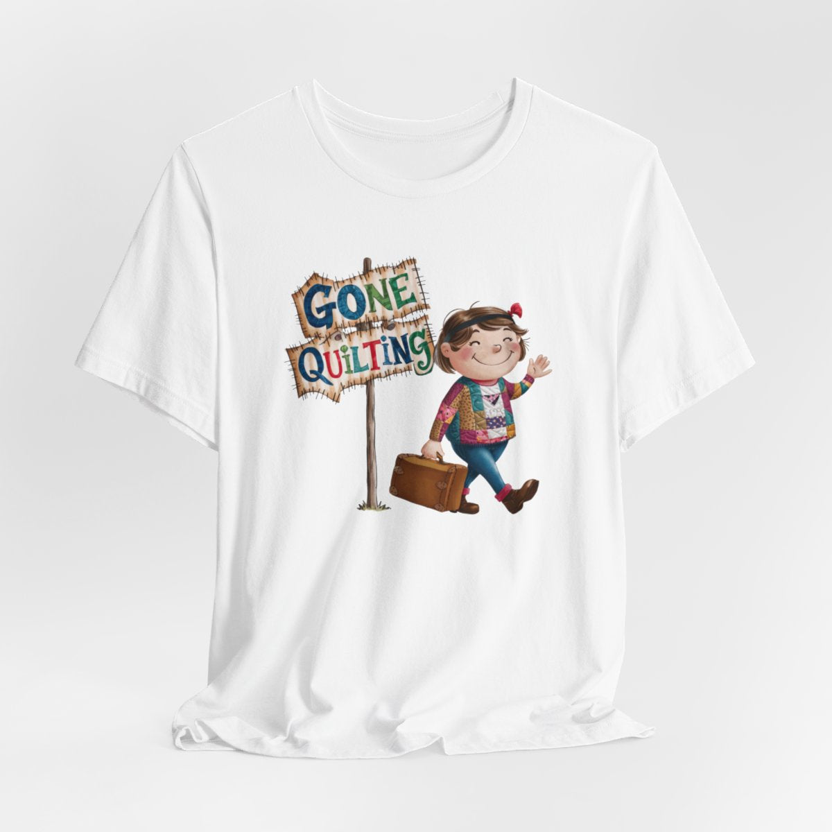 A Whitefun quilting T-Shirt with a cartoon illustration of a smiling girl wearing a patchwork jacket, carrying a suitcase next to a wooden sign that reads "Gone Quilting" in colorful letters.