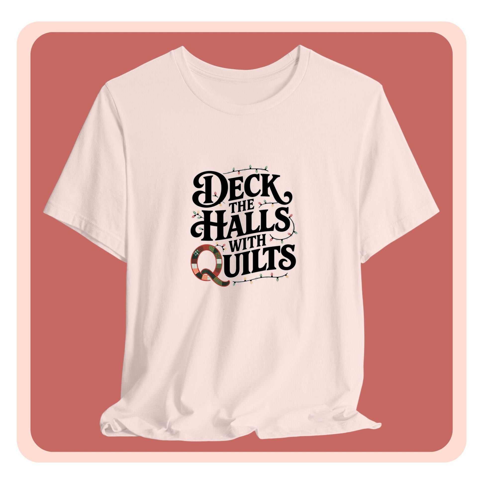 A christmas quilting t-shirt featuring the phrase "Deck the Halls with Quilts," adorned with holiday lights and quilting-inspired elements, including a quilted 'Q' for a humorous touch.