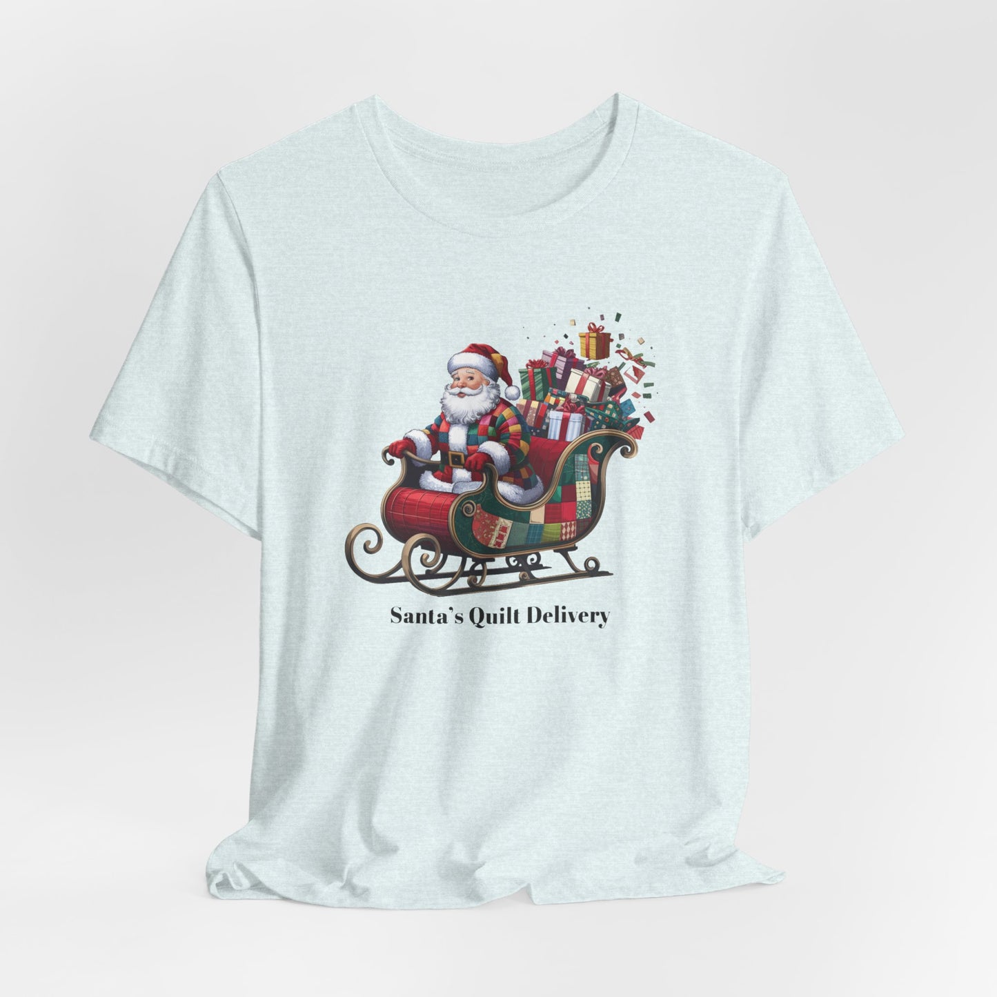 A Heather Ice Blue christmas quilting t-shirt featuring Santa Claus wearing a patchwork quilt coat, sitting in a sleigh filled with gifts and quilts, with the phrase "Santa's Quilt Delivery" below, combining holiday cheer and quilting fun.