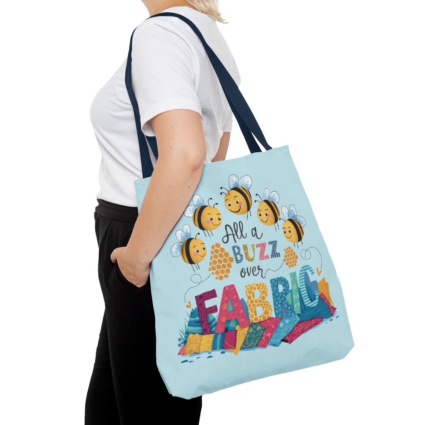 A quilting tote bag with a delightful quilting theme. Get ready to be all a buzz with excitement over your fabric stash! This playful "All a Buzz Over Fabric" 18" x 18" tote bag features adorable cartoon bees buzzing over a colorful pile of fabric, capturing the joy every quilter and sewer feels when surrounded by fabric goodness. Available in both light blue and light yellow, this cheerful design is perfect for carrying your fabric finds, sewing supplies, or everyday essentials.