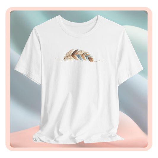 A T-Shirt with an illustration of a curving feather simulating patterned sections, resembling a patchwork quilt. The feather features a mix of floral, polka dot, and geometric designs in shades of blue, brown, and pink, with a dotted line tracing its path.