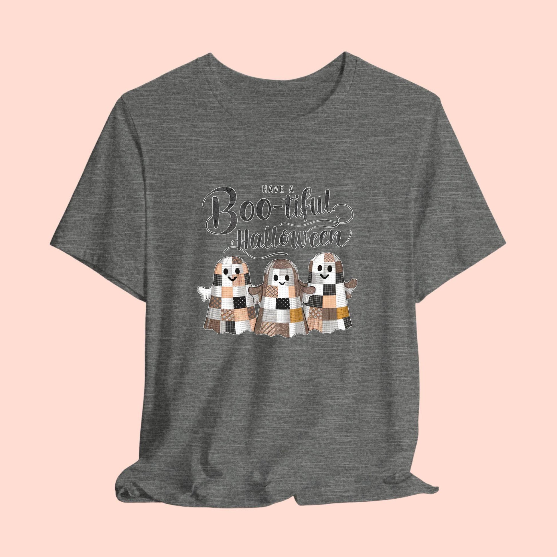 A Halloween Quilting T-Shirt featuring three smiling patchwork ghosts made of various quilt patterns in autumn colors. Text reads "Have a Boo-tiful Halloween" in stylized lettering. Perfect for quilters who love Halloween.
