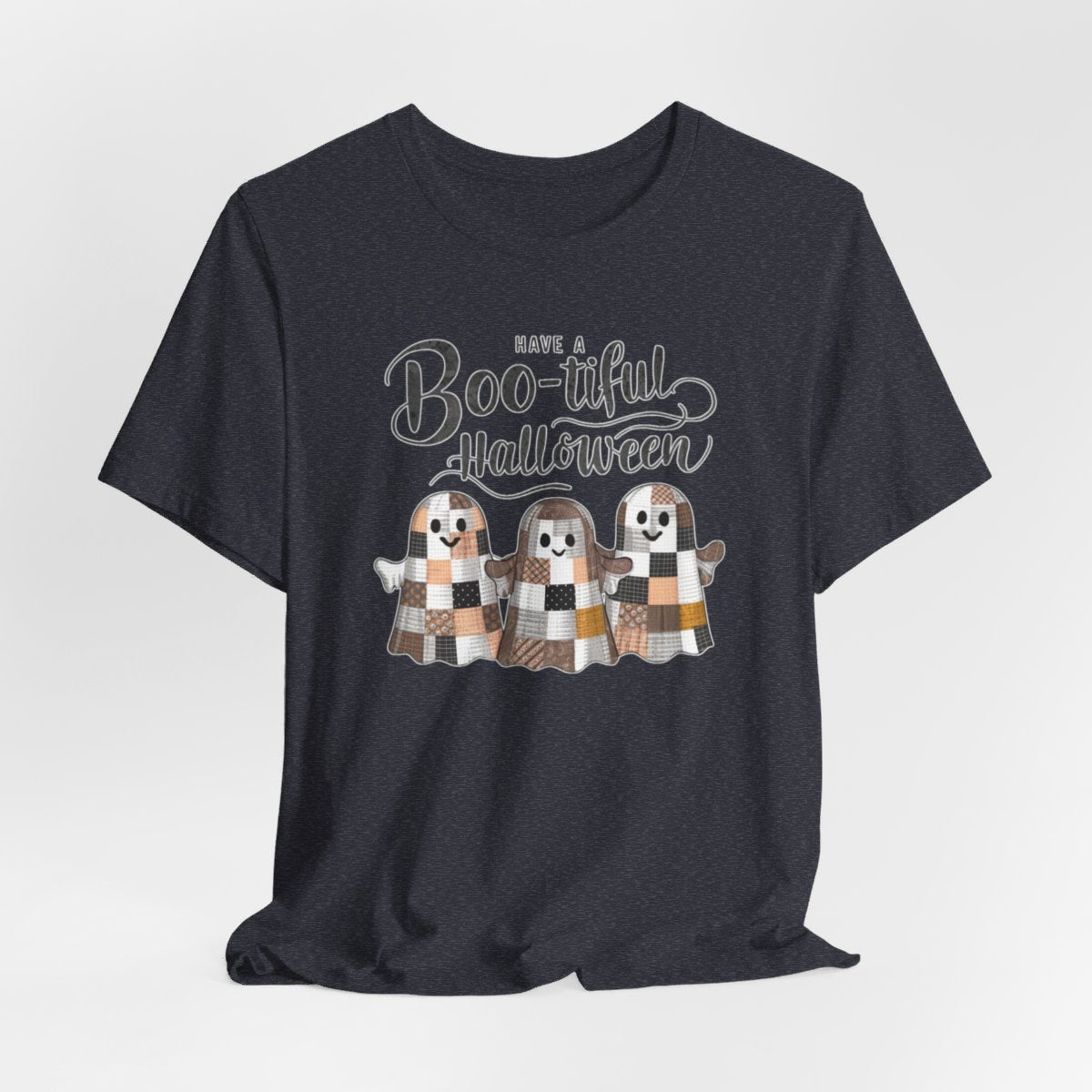 A Halloween Quilting T-Shirt featuring three smiling patchwork ghosts made of various quilt patterns in autumn colors. Text reads "Have a Boo-tiful Halloween" in stylized lettering. Perfect for quilters who love Halloween.