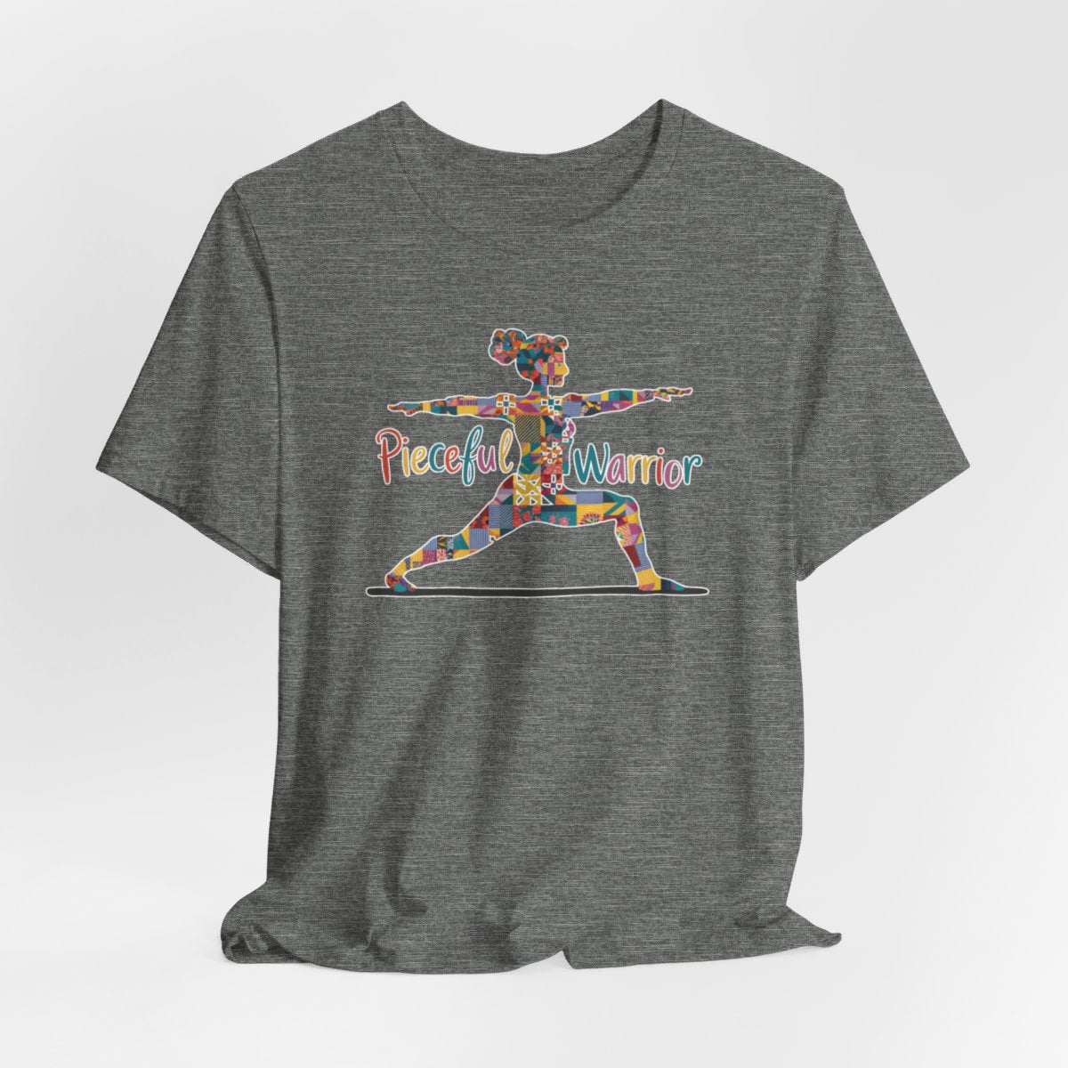 A Deep Heather Tee featuring a colorful patchwork silhouette of woman in yoga warrior pose. Text reads "Pieceful Warrior" in multicolored lettering.