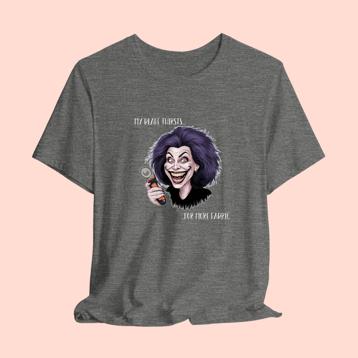 A T-shirt showing a cartoonish character with wild purple hair and an exaggerated grin, holding a rotary cutter. Text reads "My blade thirsts... for more fabric", humorously depicting a quilter's endless desire for new materials.