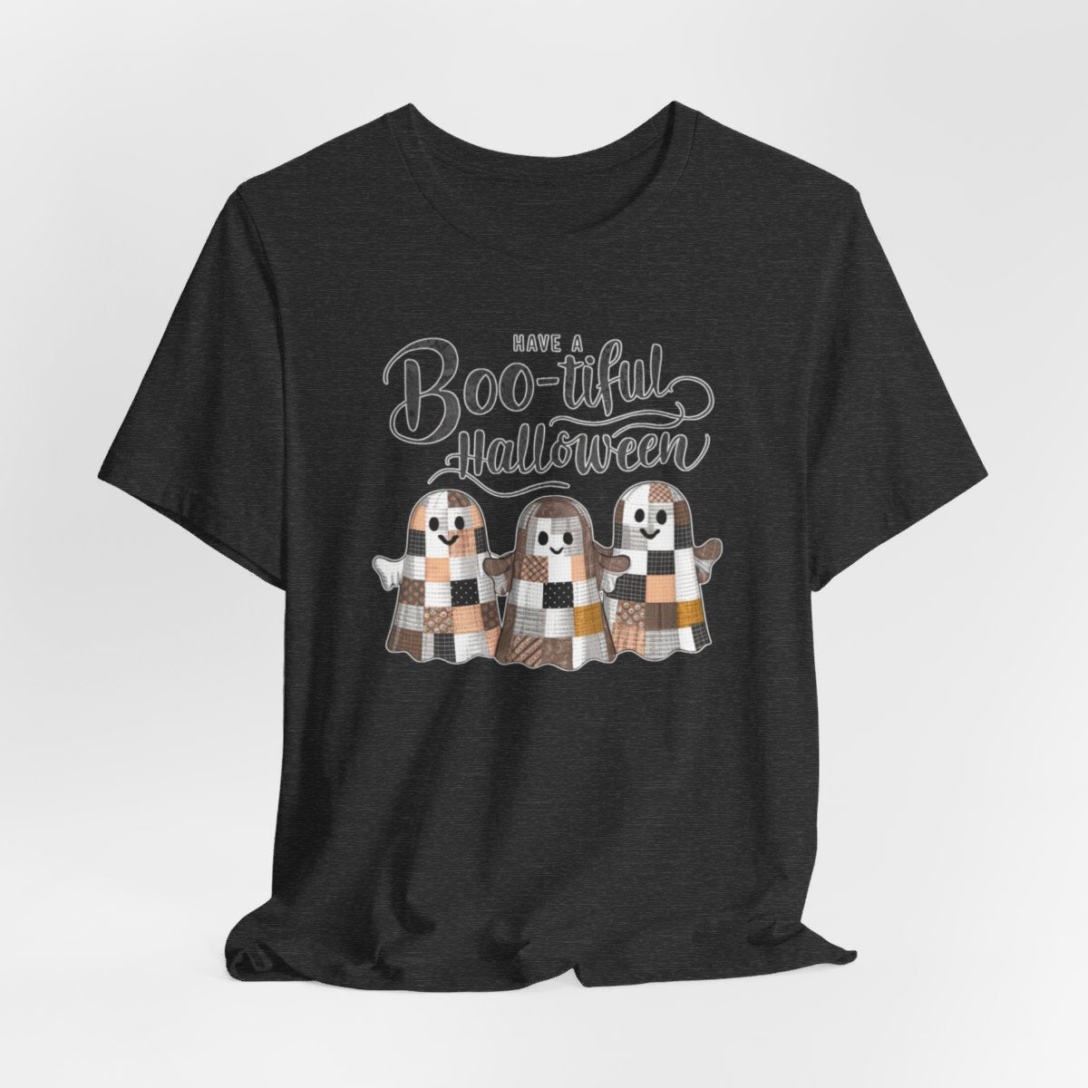 A Halloween Quilting T-Shirt featuring three smiling patchwork ghosts made of various quilt patterns in autumn colors. Text reads "Have a Boo-tiful Halloween" in stylized lettering. Perfect for quilters who love Halloween.