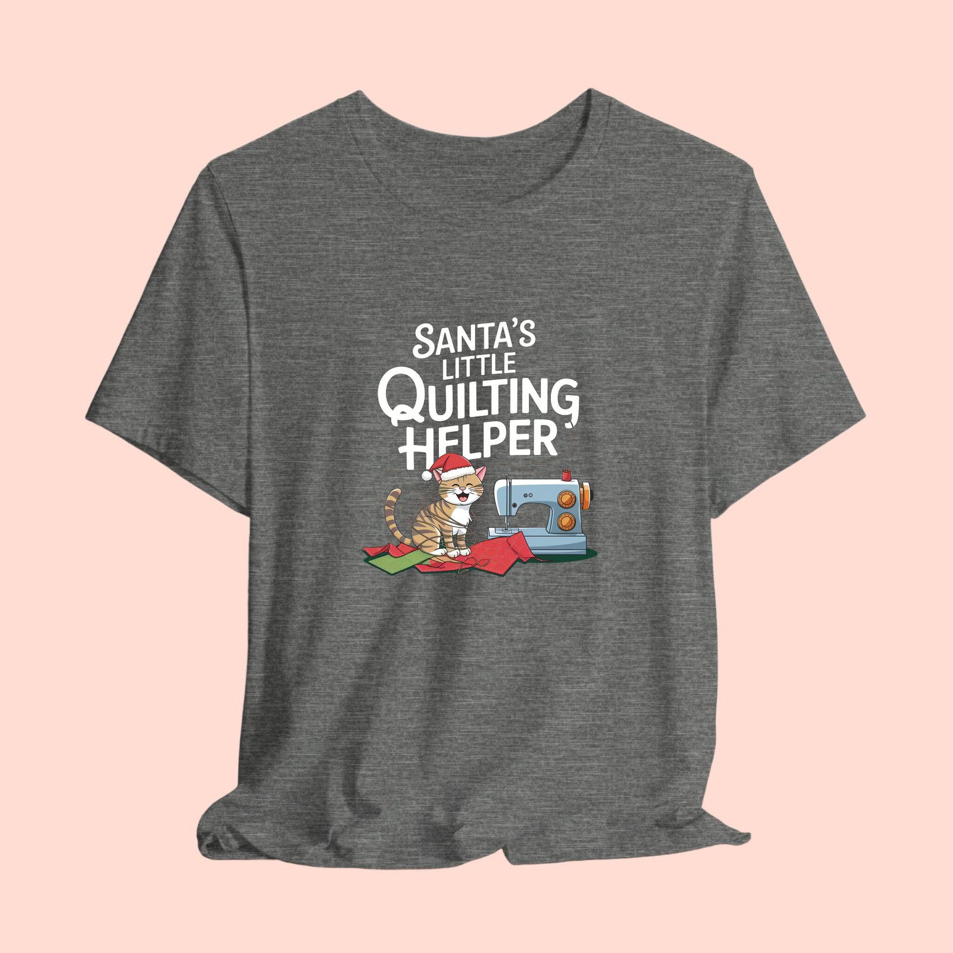 A christmas quilting t-shirt featuring a playful cat wearing a Santa hat is tangled in thread next to a sewing machine, with the phrase "Santa's Little Quilting Helper" above, combining quilting and holiday humor.