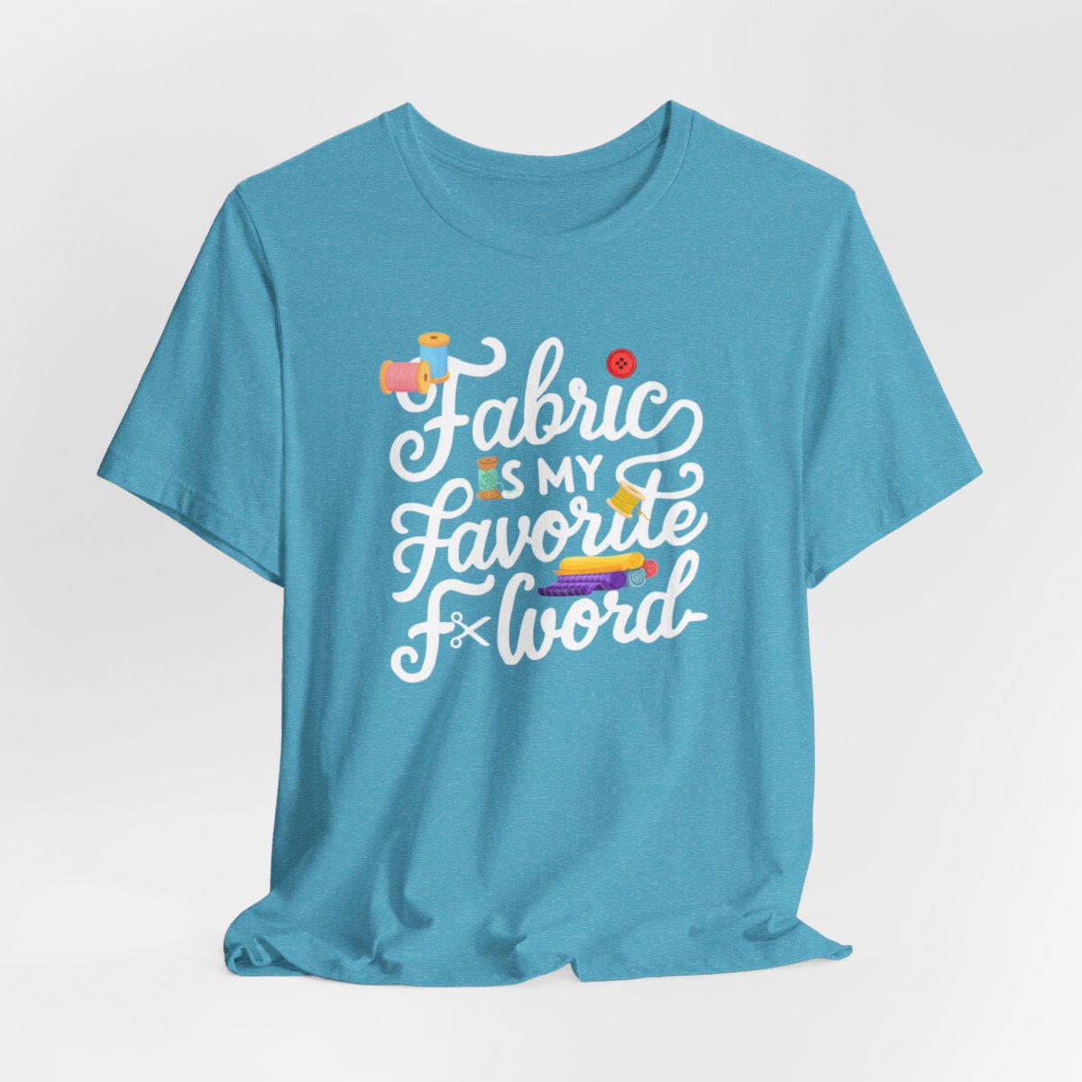 A Heather Aqua T-Shirt with the phrase Fabric is My Favorite F-Word in a bold font with thread, buttons, and fabric bolts