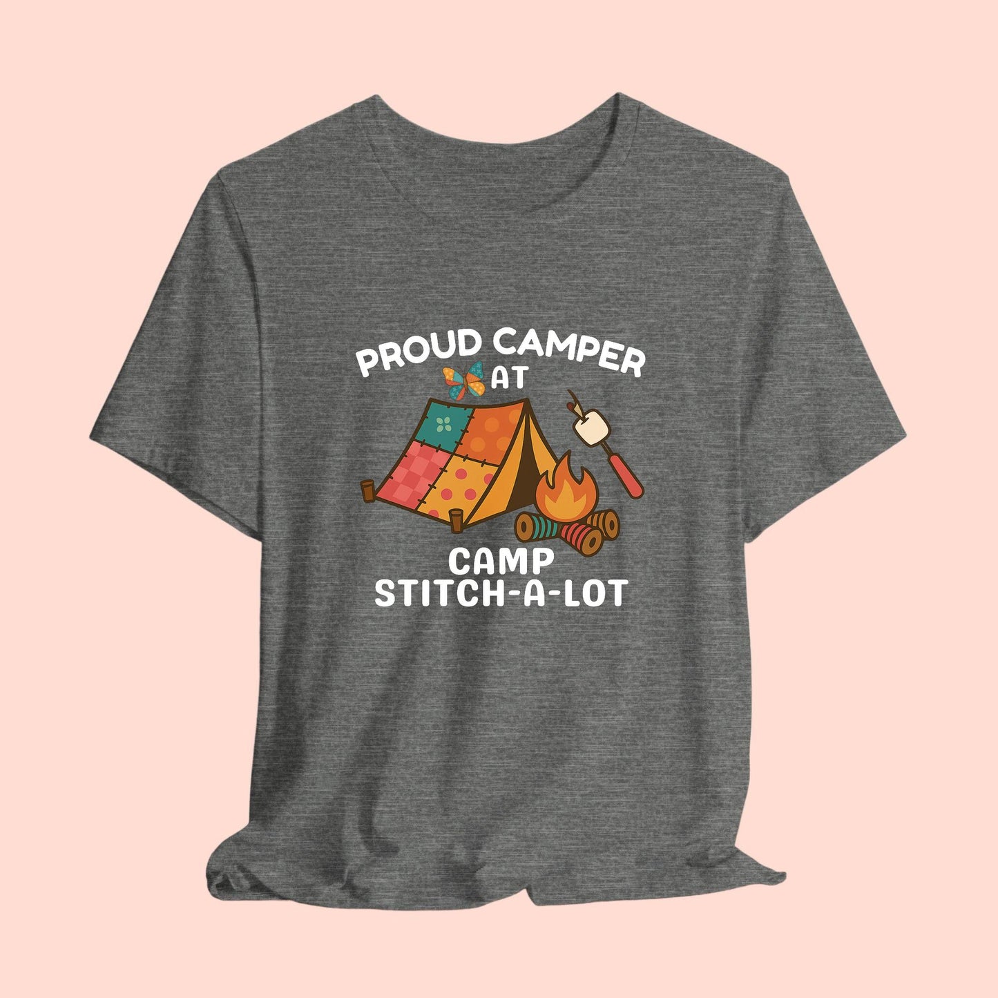 A A t-shirt featuring a colorful design with a patchwork tent, thread spool campfire, marshmallow on a seam ripper stick, and a butterfly. Text reads "Proud Camper at Camp Stitch-a-Lot." Fun gift for quilting retreats.