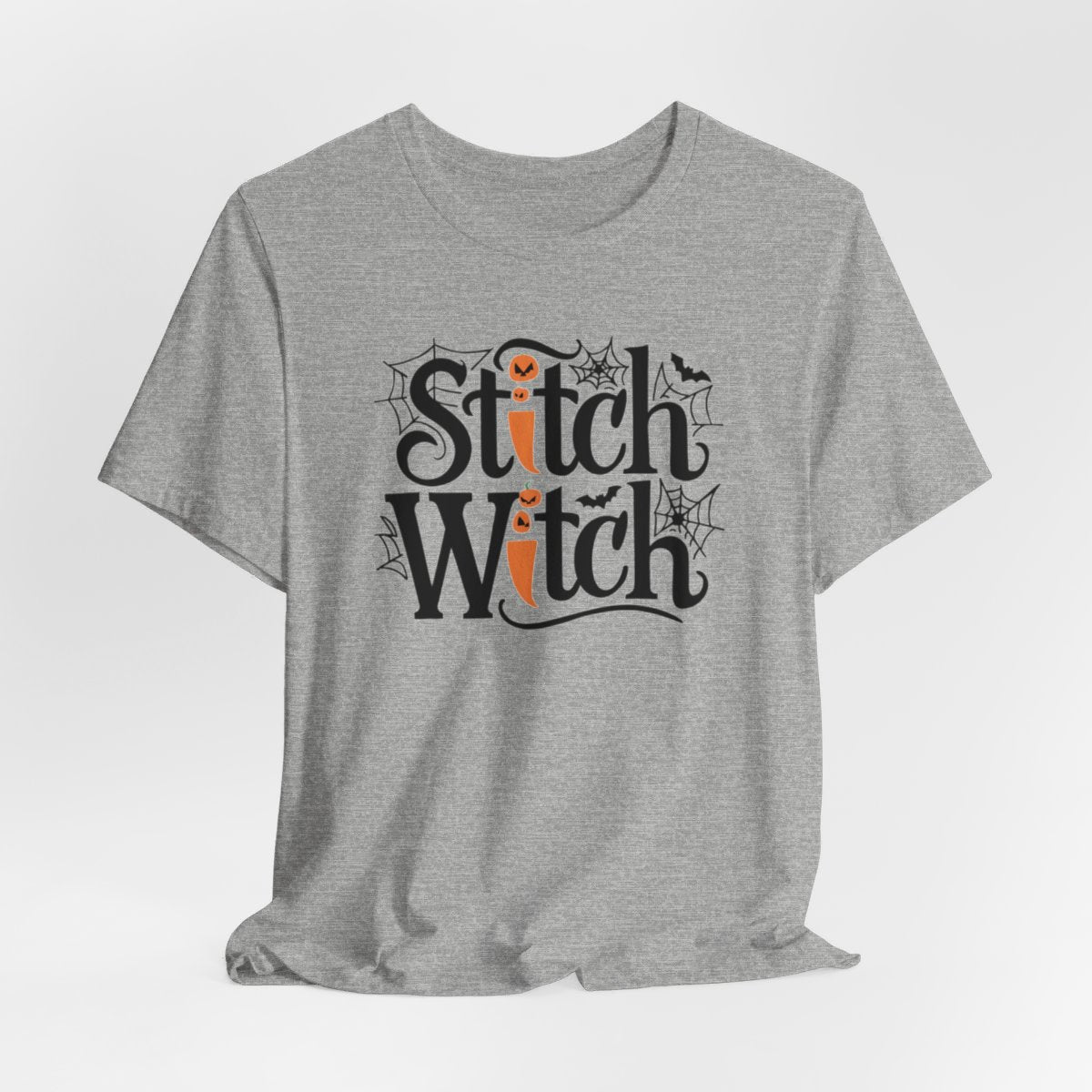 T-shirt design with "Stitch Witch" text in Halloween-themed typography. Jack-o'-lanterns, spiderwebs, and bats decorate the letters. The "i" in "Stitch" resembles a sewing needle. Ideal for quilters who love Halloween.